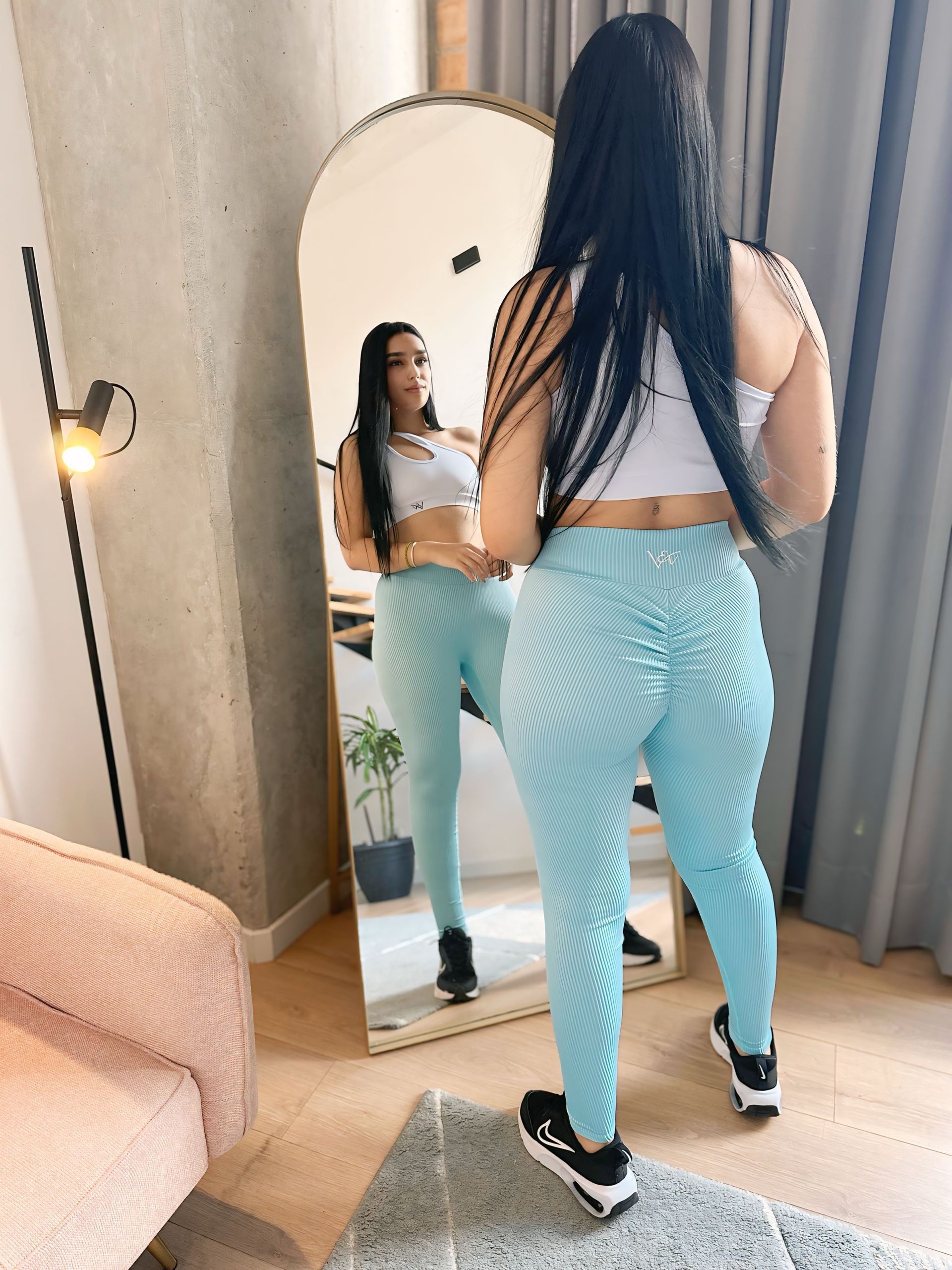 A woman is standing in front of a mirror in a room.