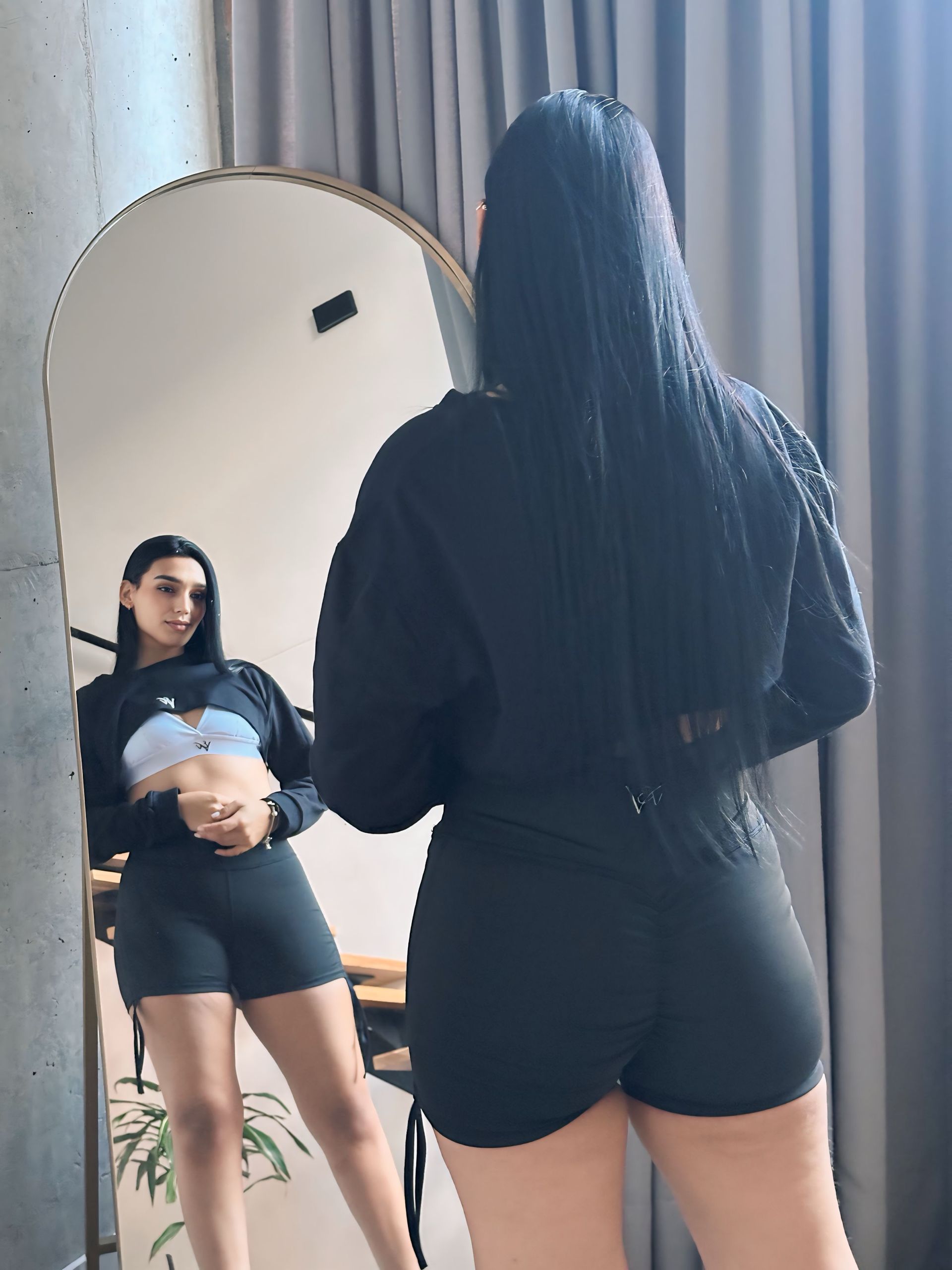 A woman is standing in front of a mirror looking at herself.