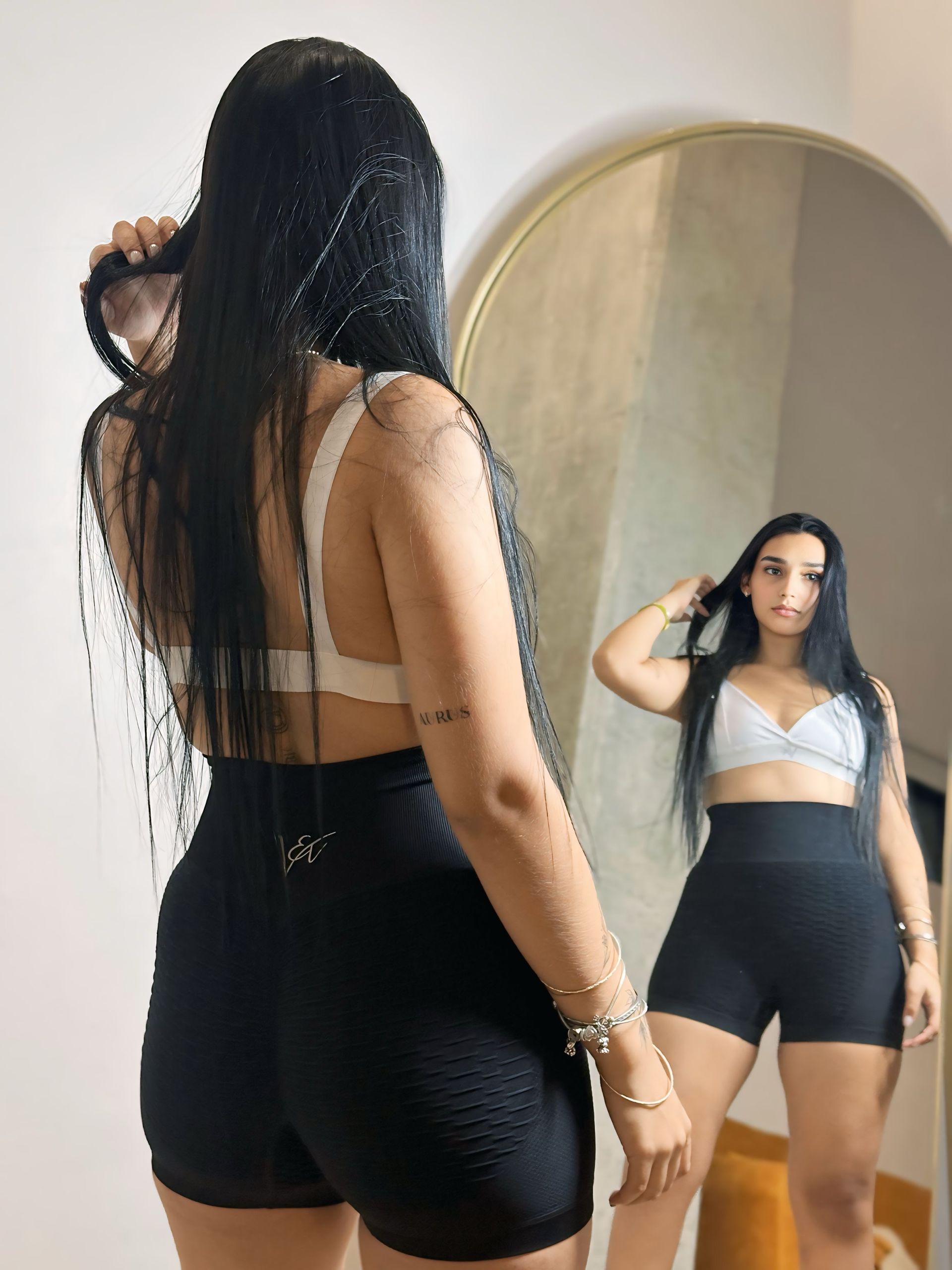 A woman is brushing her hair in front of a mirror.