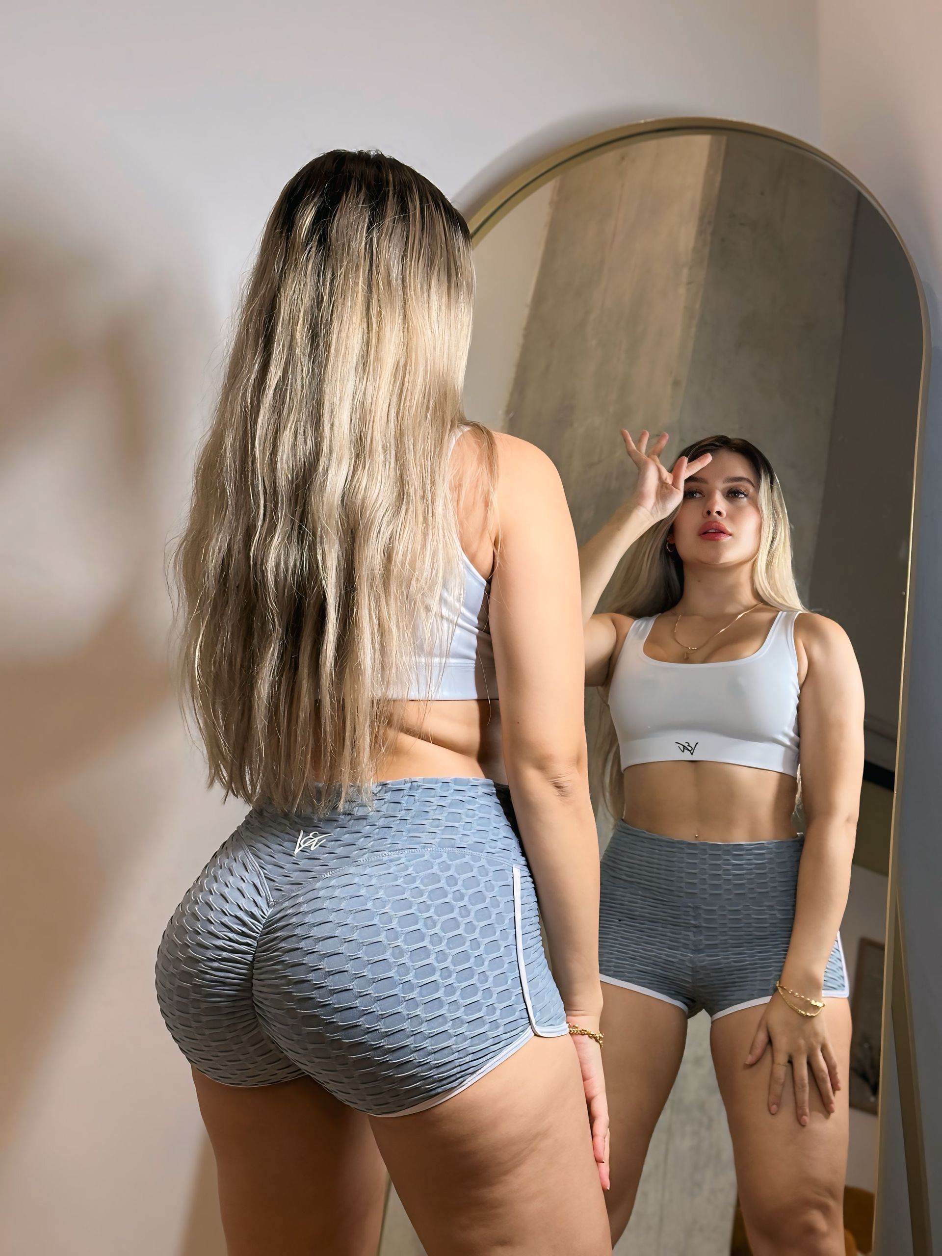 A woman is standing in front of a mirror looking at herself.