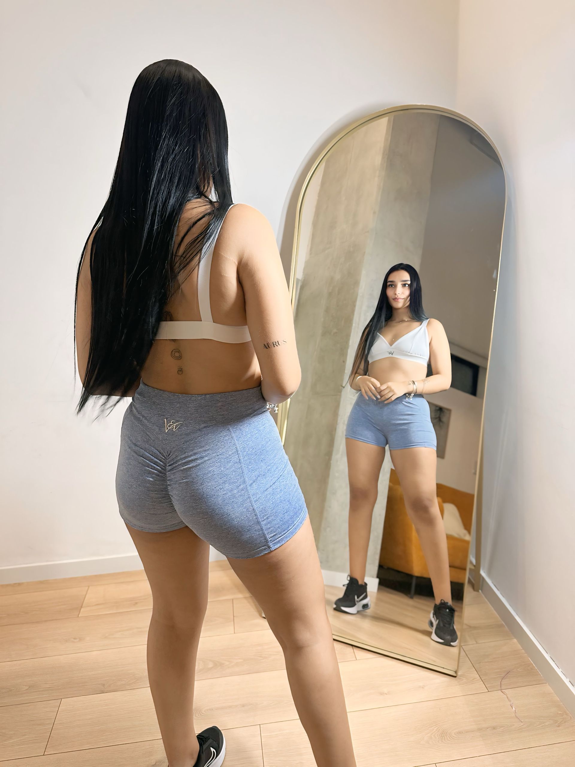 A woman is standing in front of a mirror in a room.