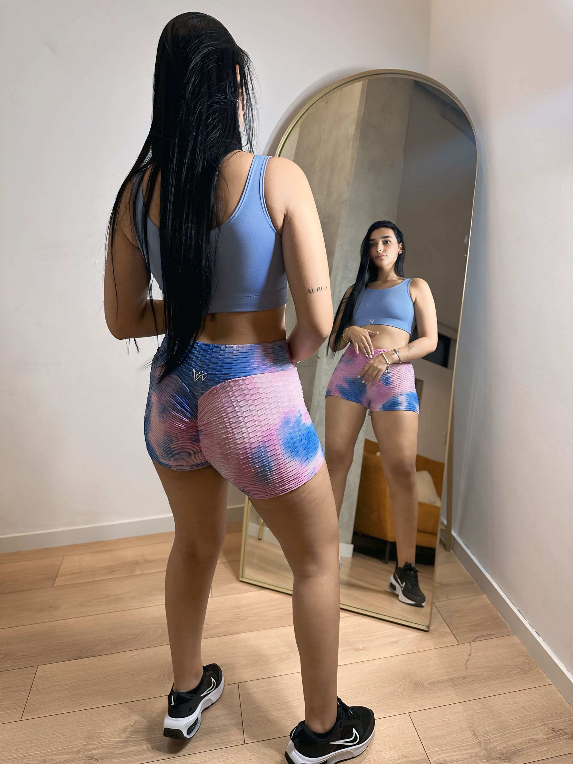 A woman is standing in front of a mirror in a room.