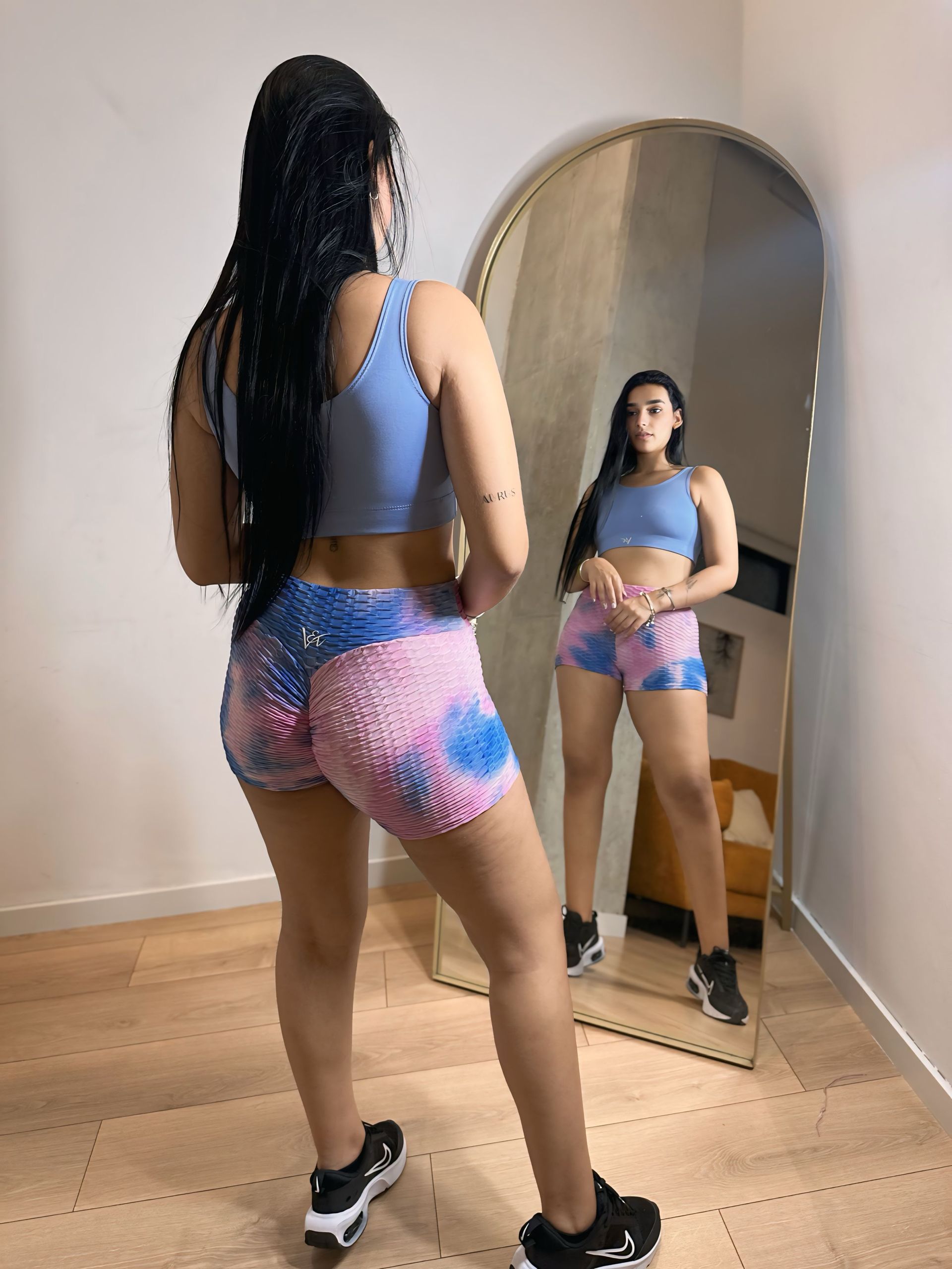 A woman is standing in front of a mirror in a room.