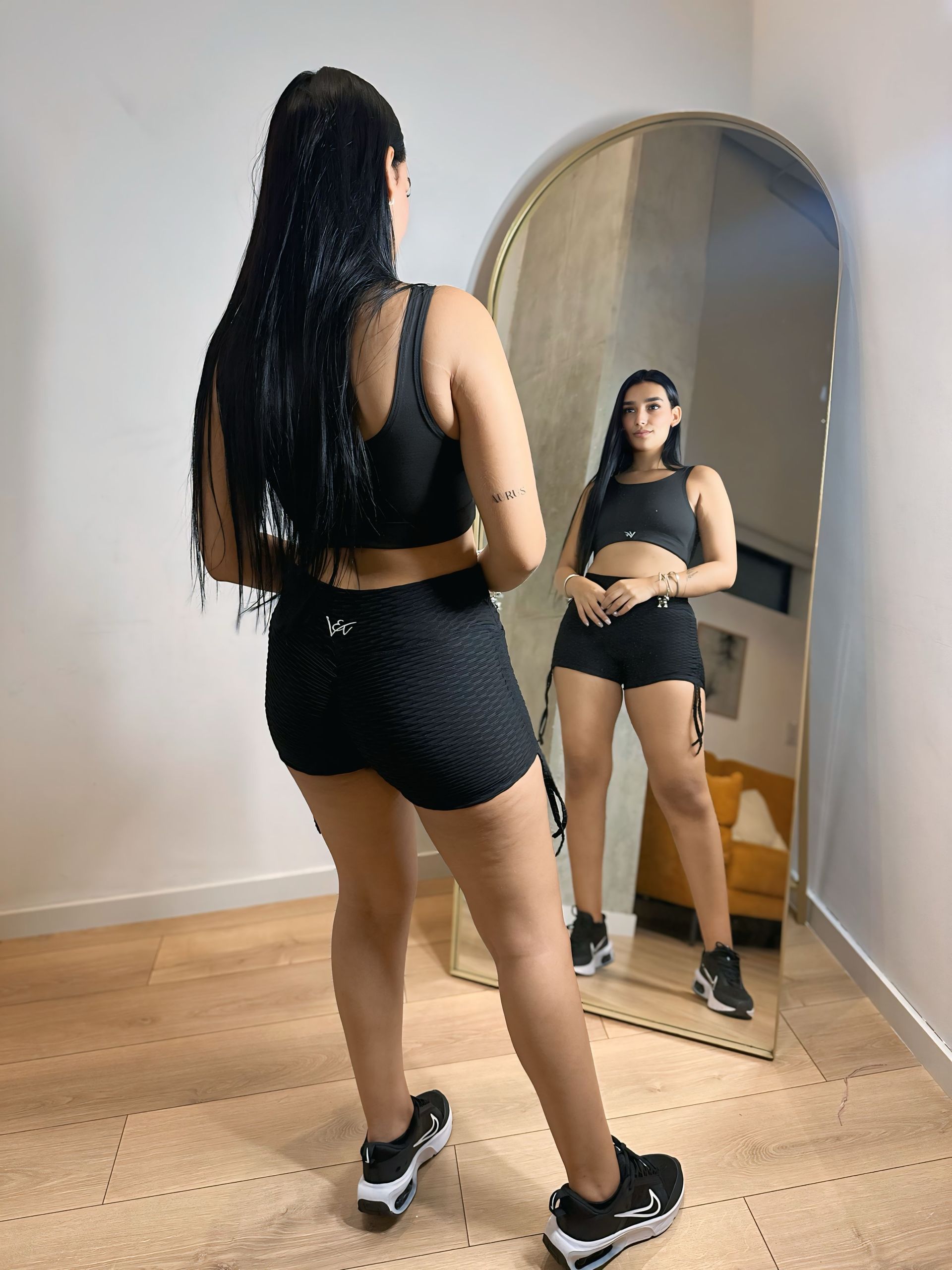 A woman is standing in front of a mirror in a room.