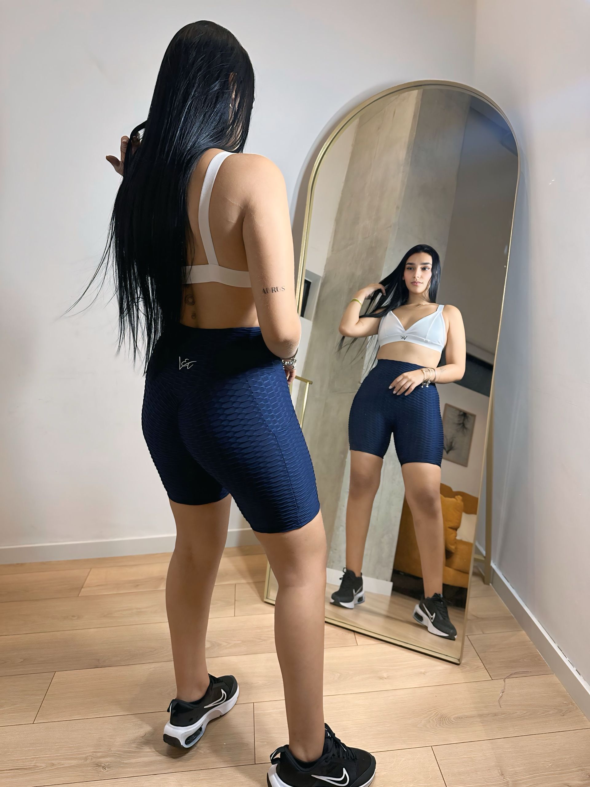 A woman is standing in front of a mirror in a room.