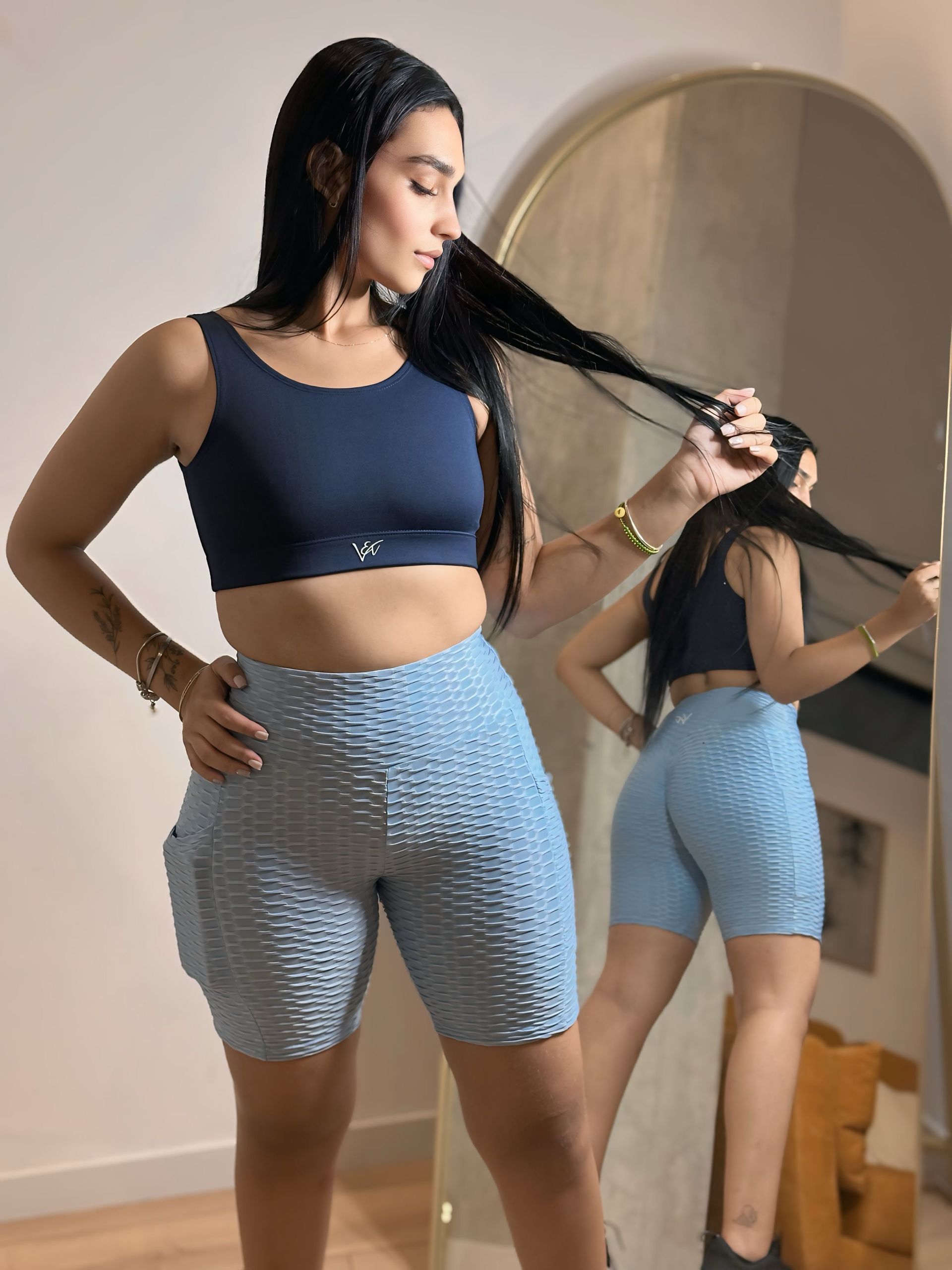 A woman is standing in front of a mirror holding her hair.
