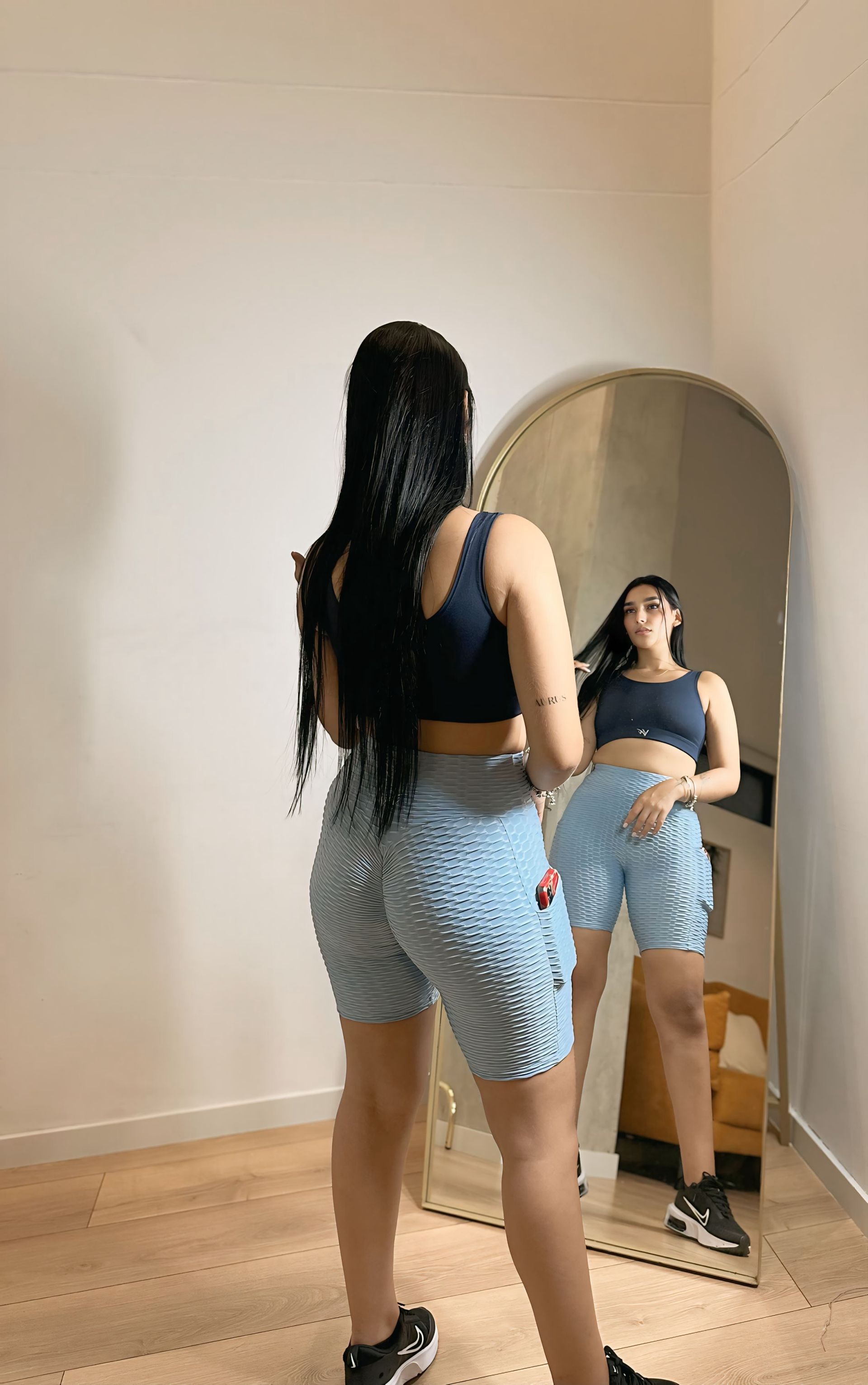 A woman is standing in front of a mirror in a room.