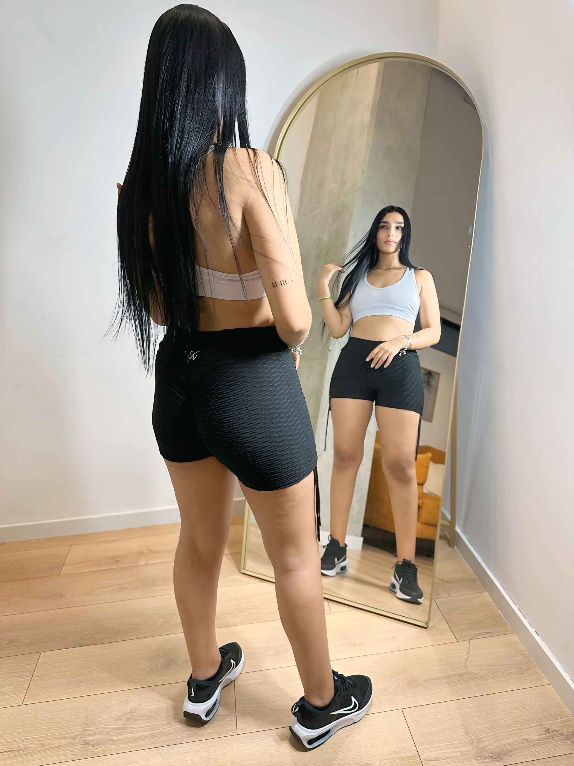 A woman is standing in front of a mirror in a room.