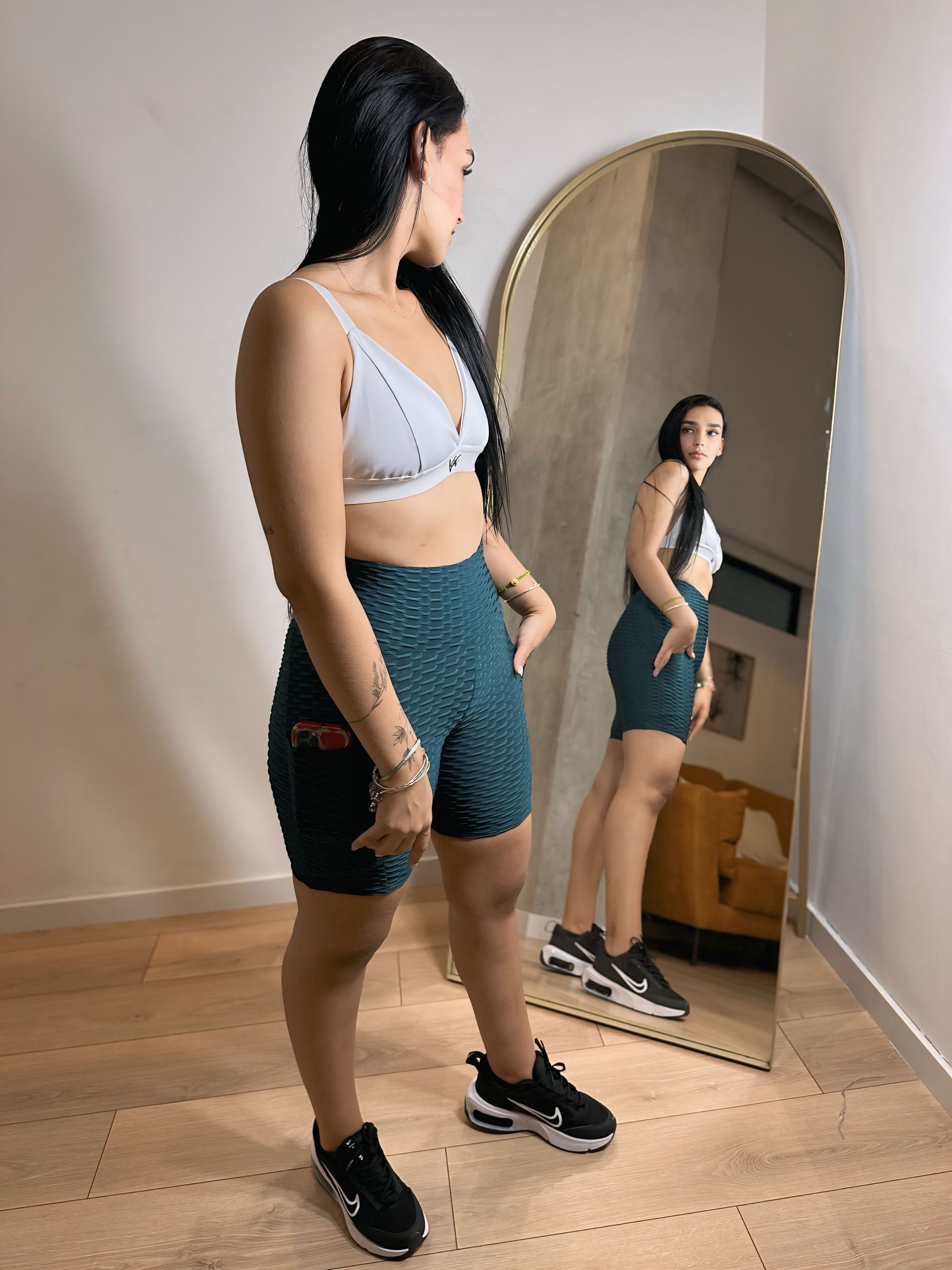 A woman is standing in front of a large mirror.