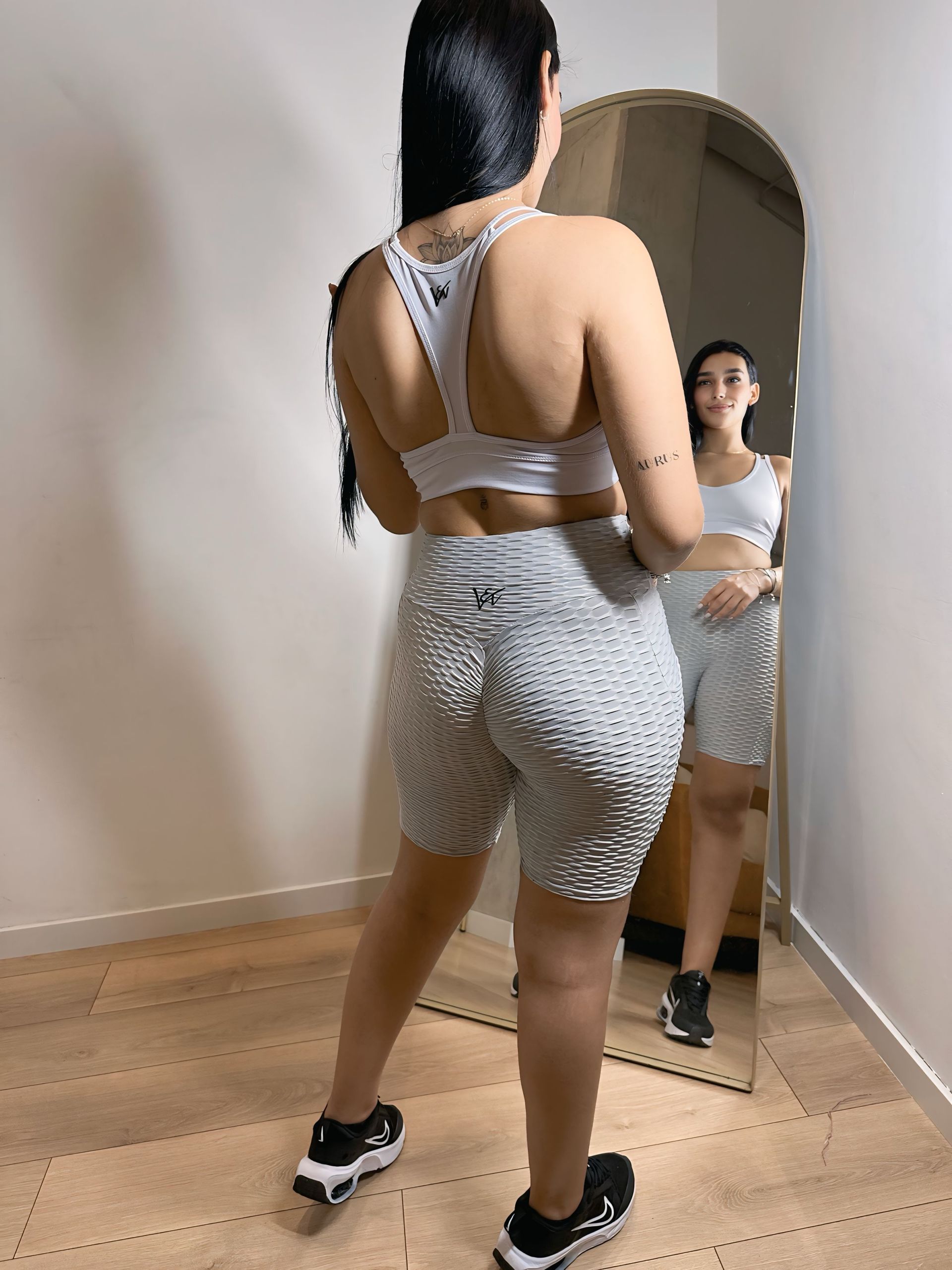 A woman is standing in front of a mirror in a room.