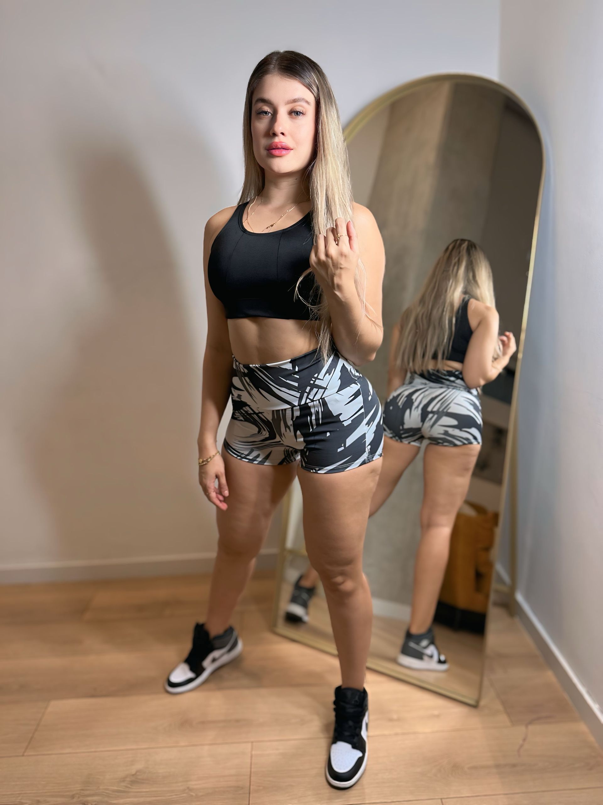 A woman is standing in front of a mirror in a room.