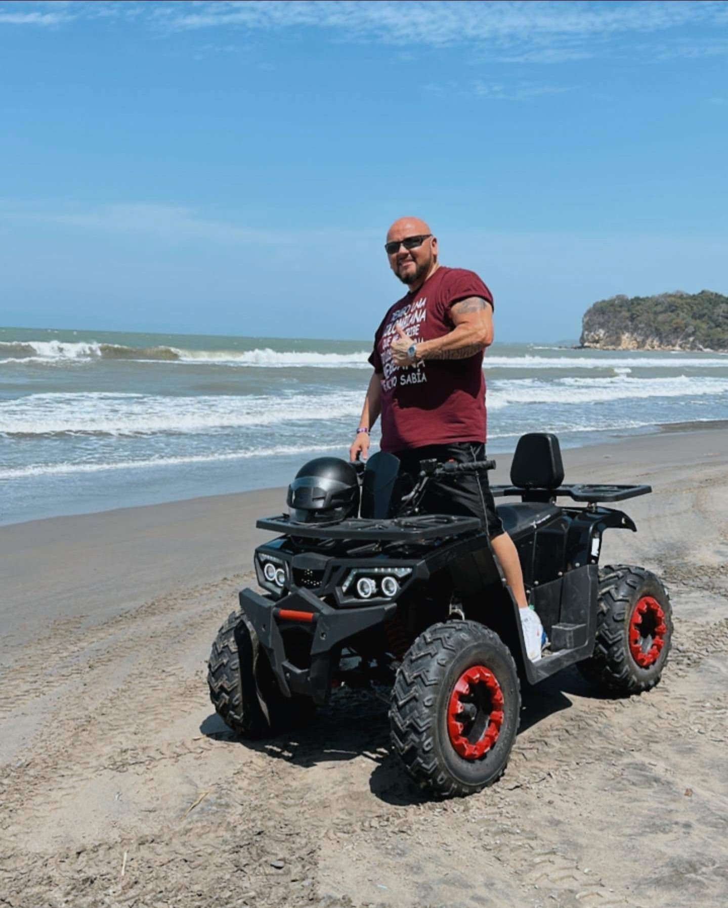 A man is riding an atv on the beach.