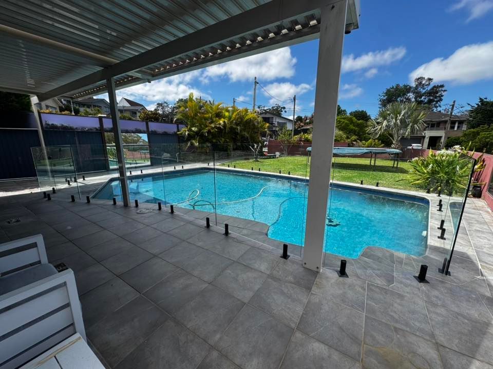 A Backyard View Featuring a Swimming Pool Enclosed by Glass Fencing — ClearView Glass Pool Fencing In Roselands, NSW