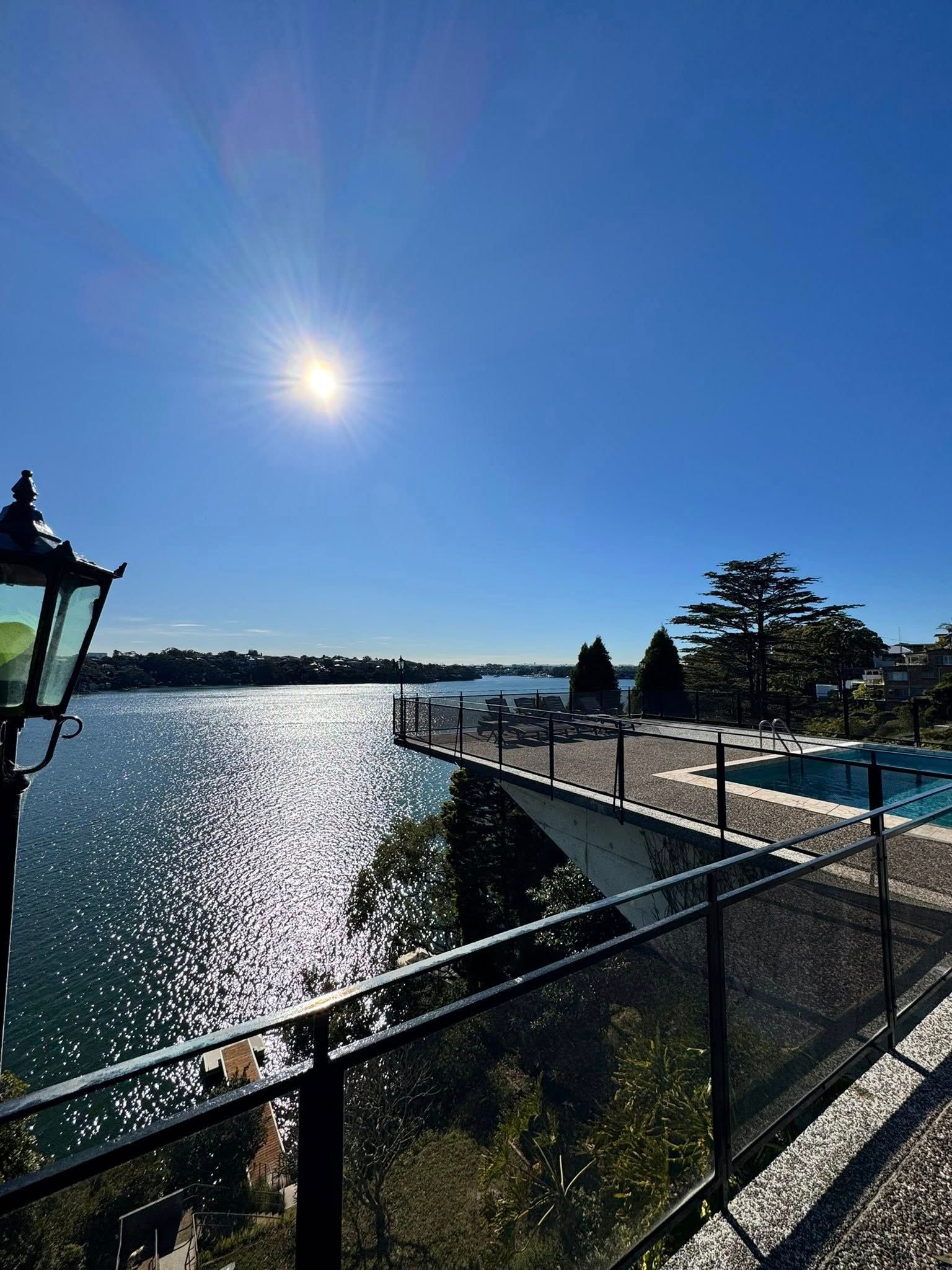 A Balcony View Deck With a Swimming Pool and a Clear Glass Fencing — ClearView Glass Pool Fencing In Sutherland Shire, NSW
