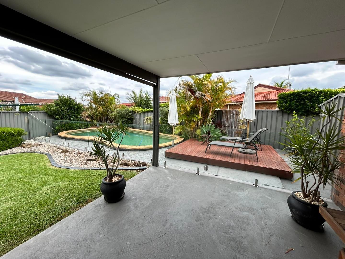 A Backyard Swimming Pool With Light Blue Water — ClearView Glass Pool Fencing In Roselands, NSW