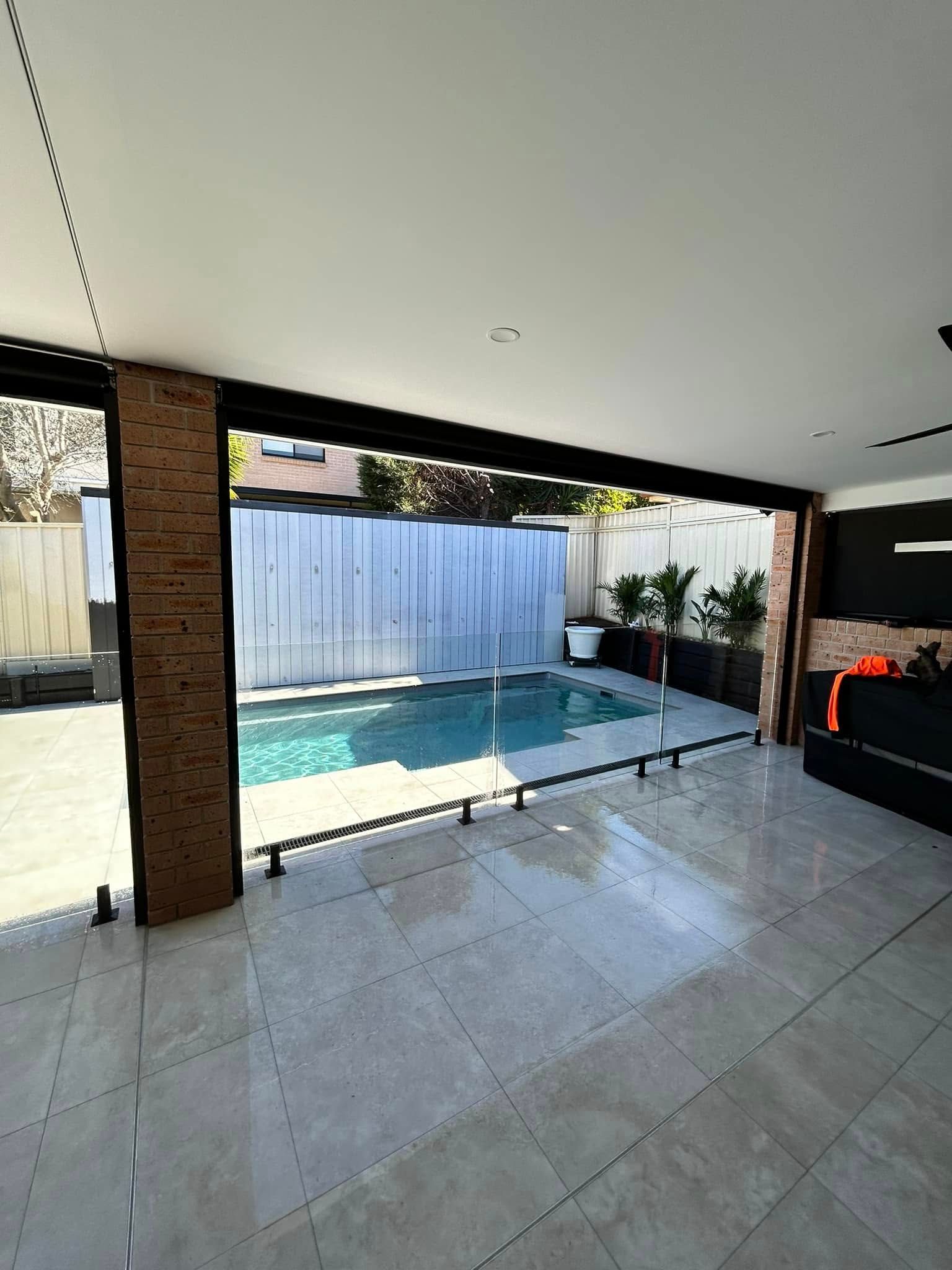 Covered patio overlooking a small turquoise pool, with tiled floor and white privacy fence — ClearView Glass Pool Fencing In Roselands, NSW