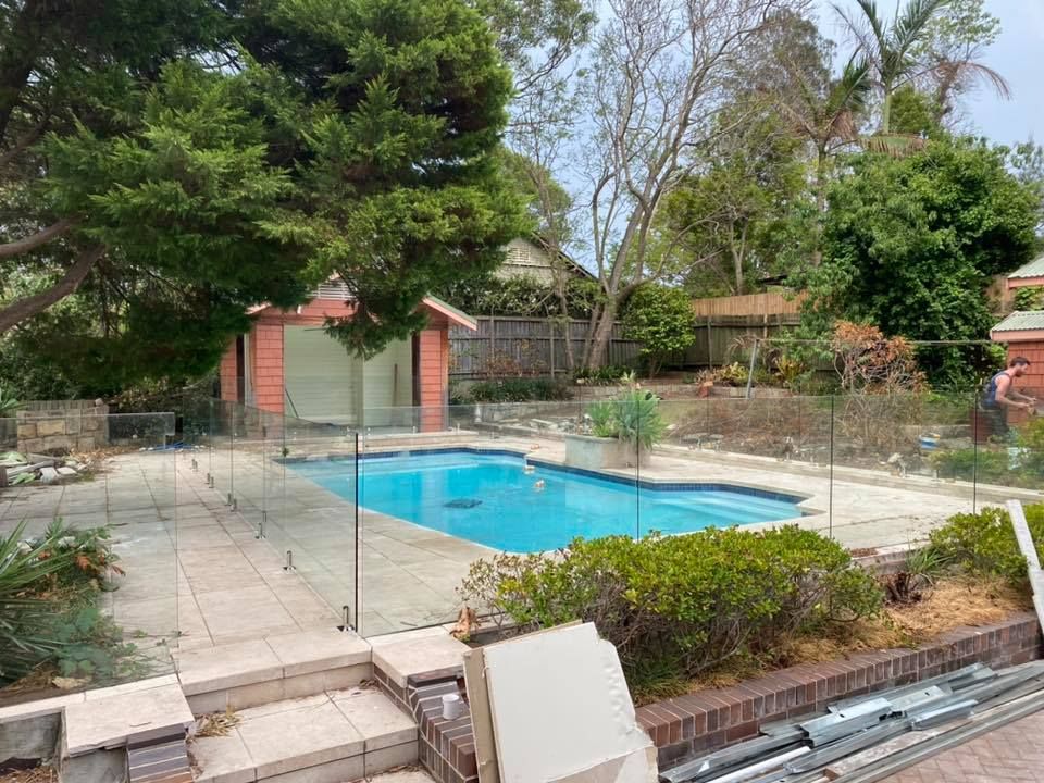 A Backyard Swimming Pool With Light Blue Water, Clear Fences — ClearView Glass Pool Fencing In Roselands, NSW