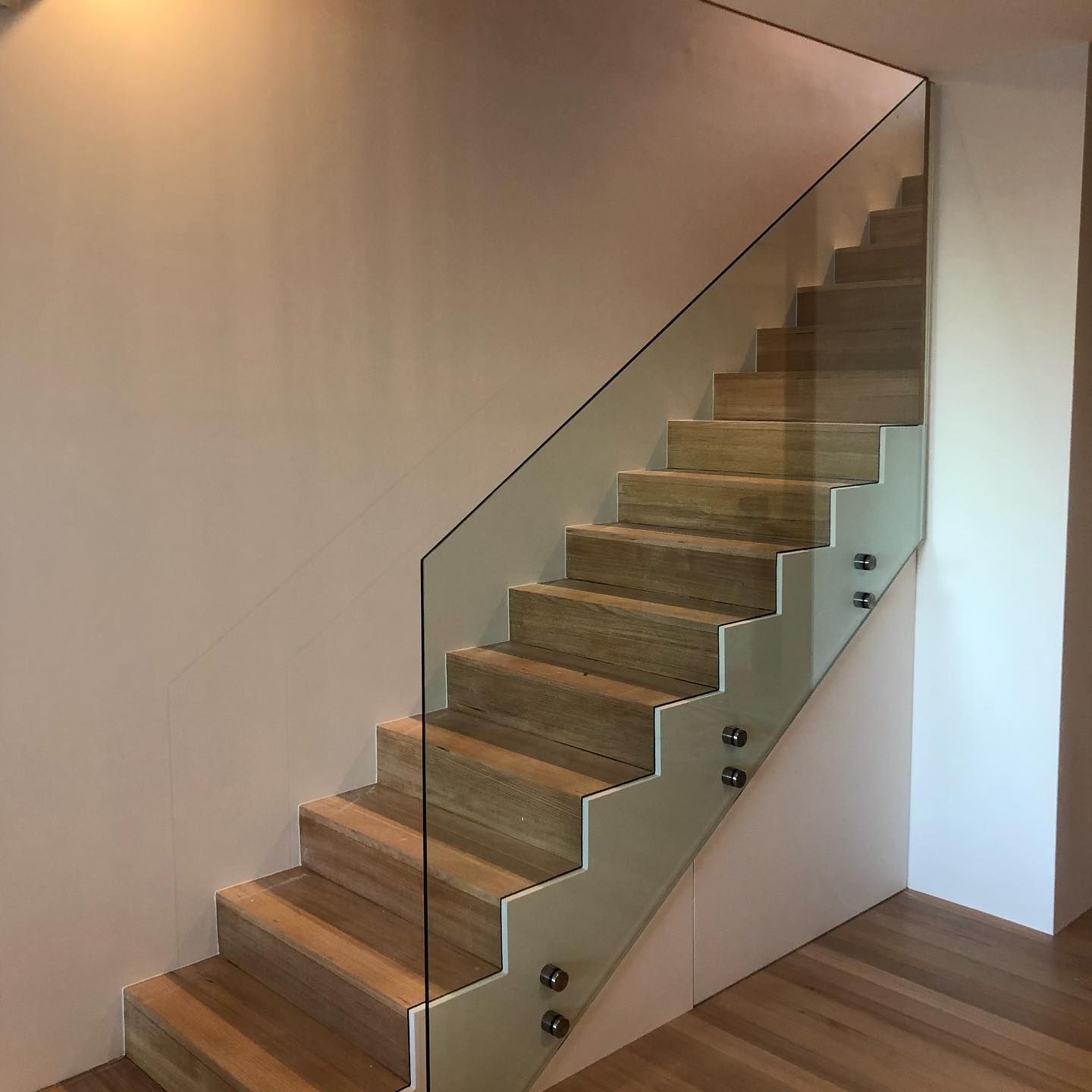 Modern staircase with wood treads and glass railing in a minimalist interior — ClearView Glass Pool Fencing In Roselands, NSW