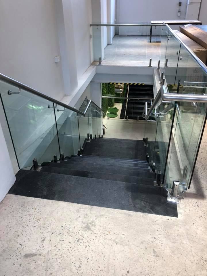 Glass-railed indoor staircase descending to a lower floor in a modern building — ClearView Glass Pool Fencing In Roselands, NSW
