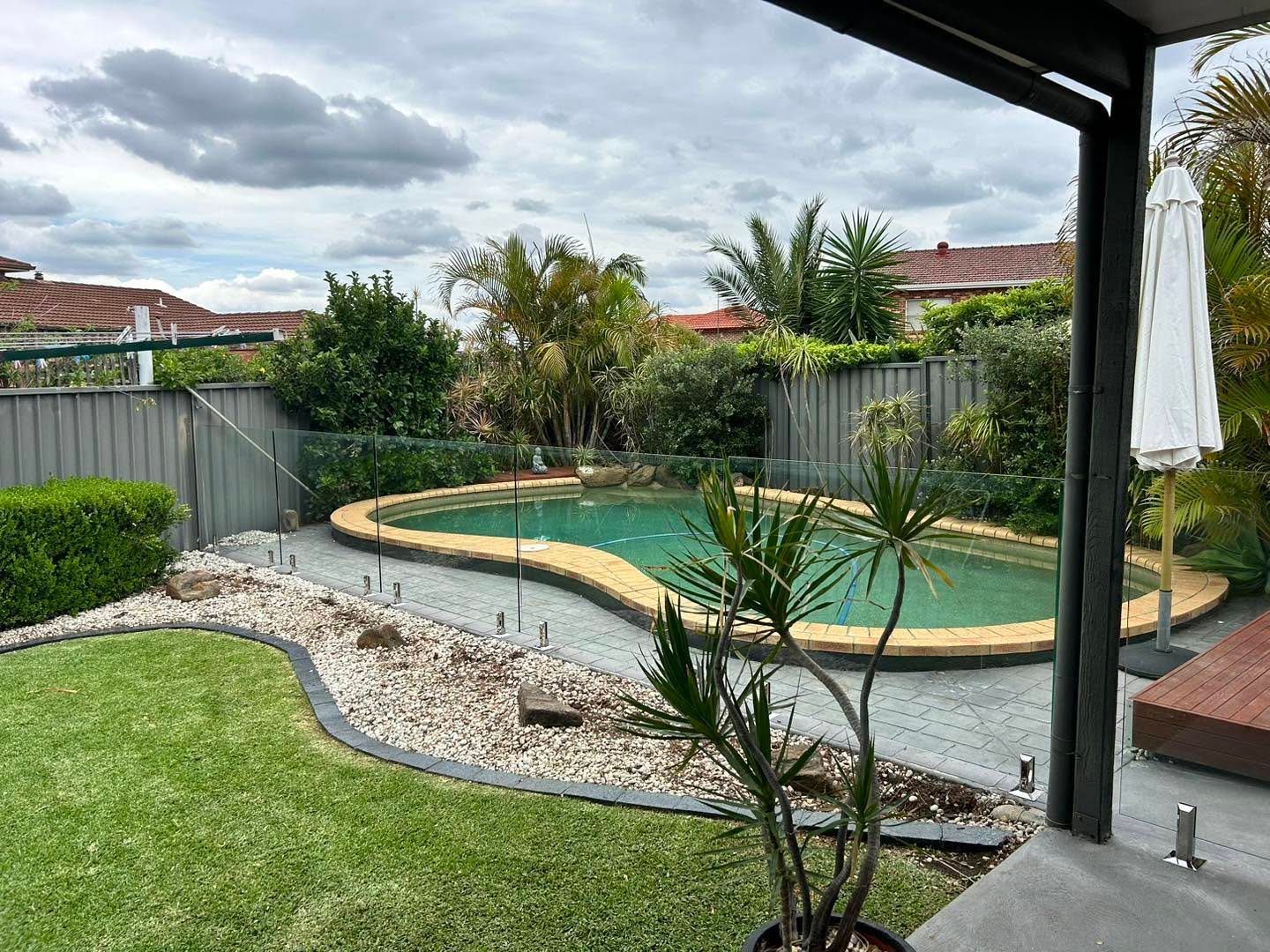 Backyard Patio With a Small Swimming Pool, Green Lawn — ClearView Glass Pool Fencing In Roselands, NSW