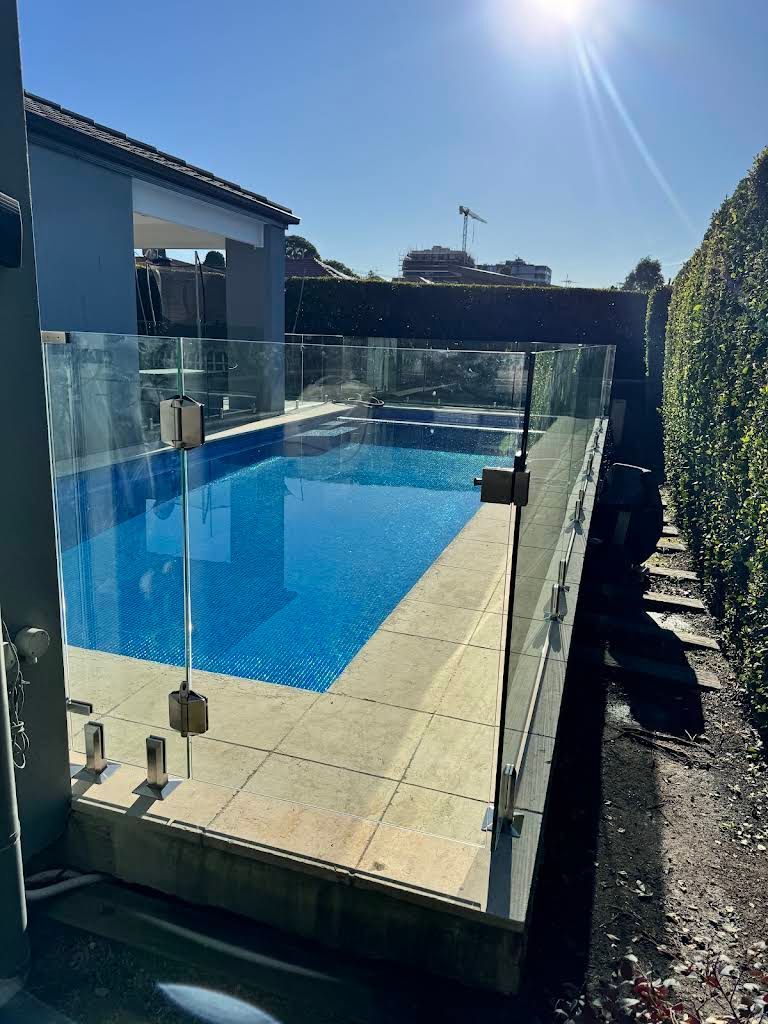 Backyard Swimming Pool With Glass Fence and Bright Sunlight — ClearView Glass Pool Fencing In Parramatta, NSW