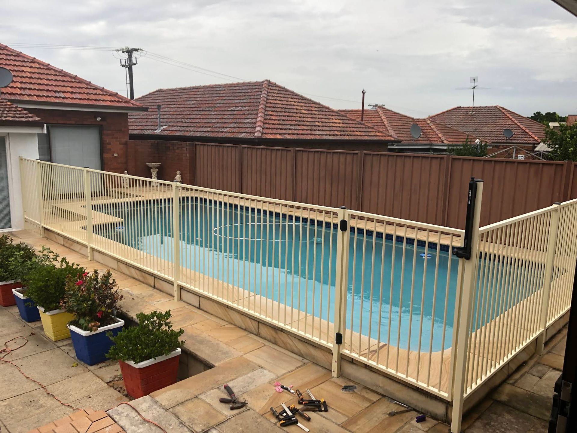 Backyard Swimming Pool With Beige Safety Fence — ClearView Glass Pool Fencing In Eastern Suburbs, NSW
