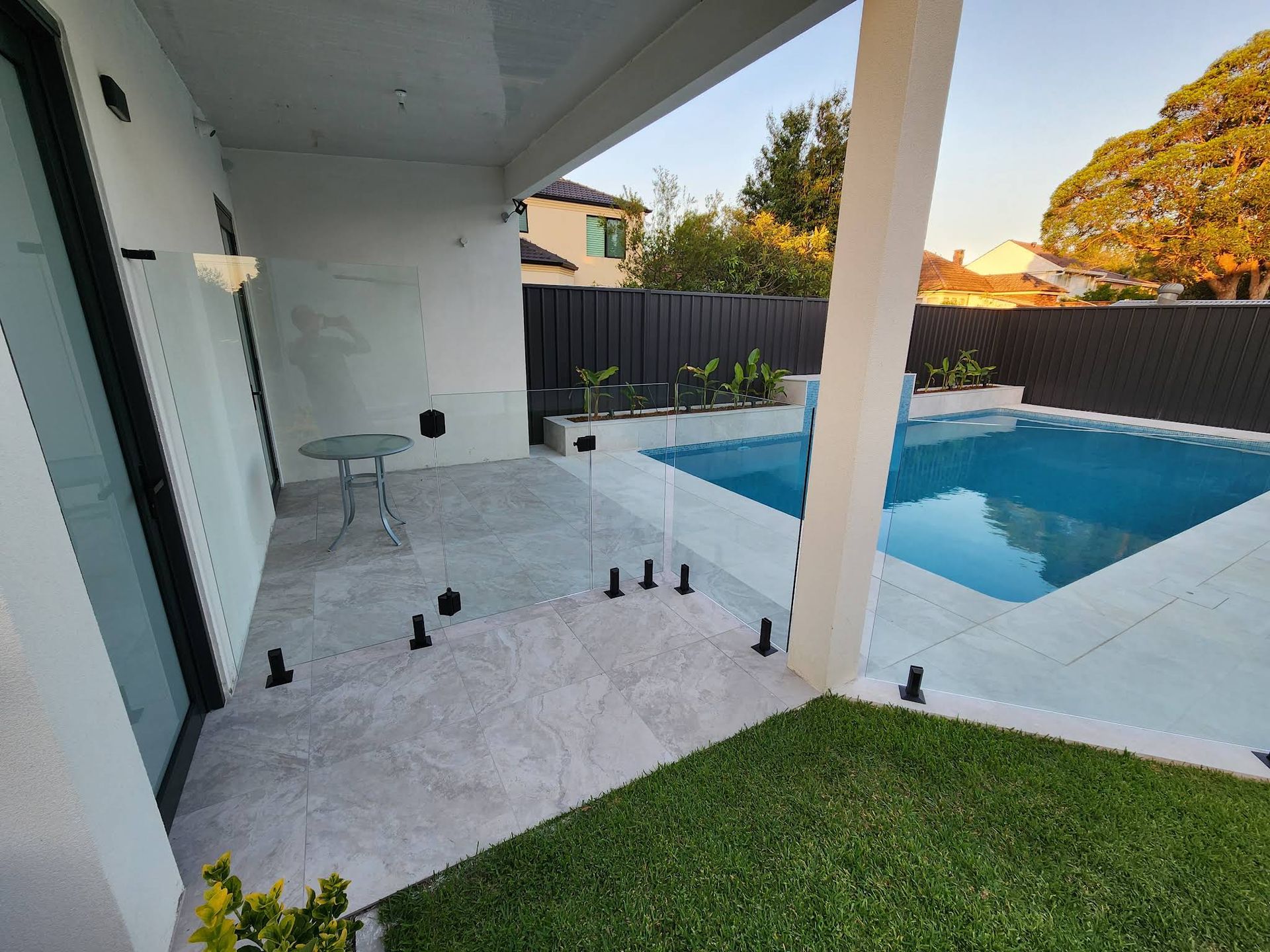Covered Patio Overlooking a Blue Backyard Pool With White Tile — ClearView Glass Pool Fencing In Sutherland Shire, NSW