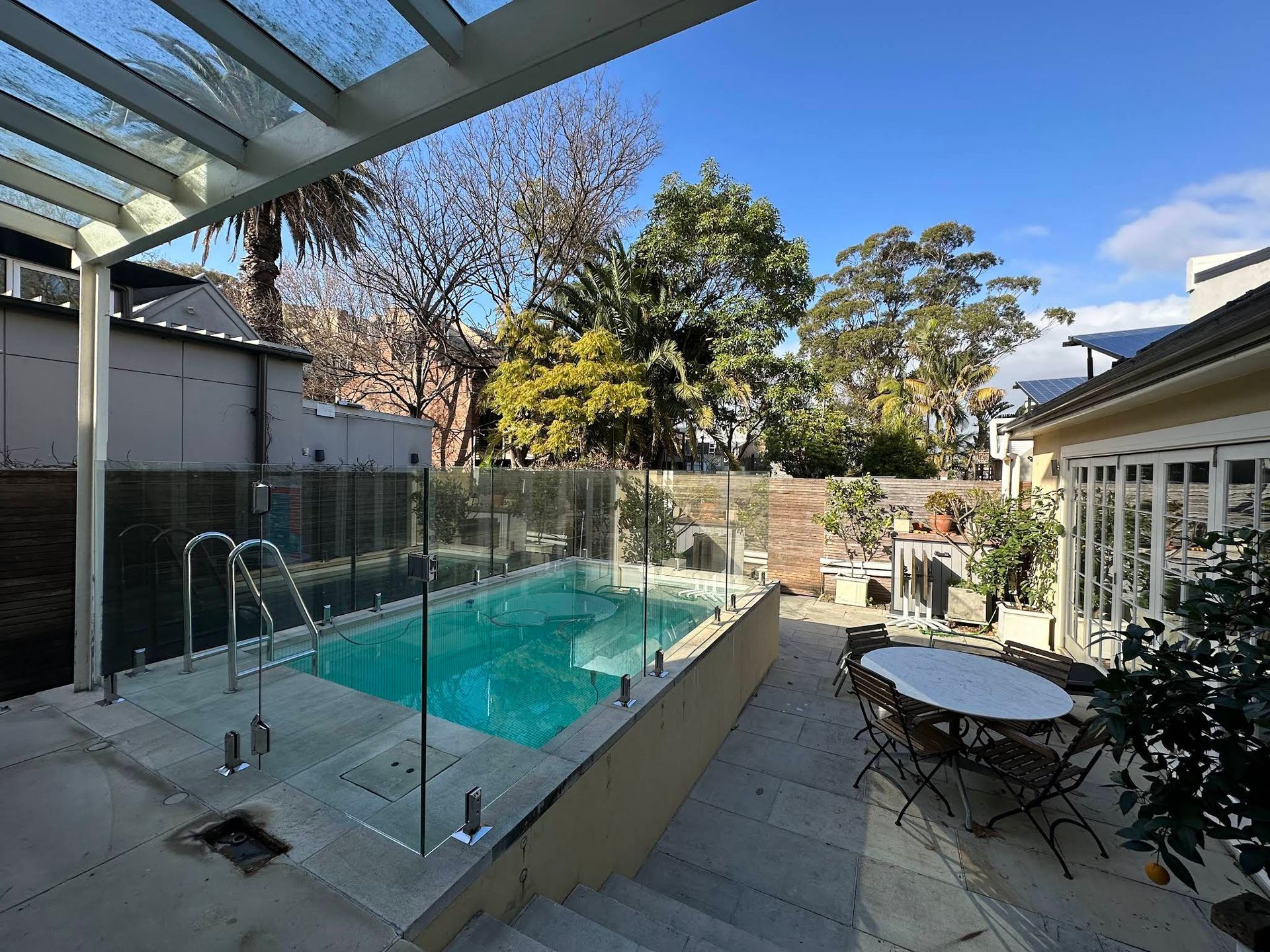 Backyard Pool With Glass Fence, Patio Table, and Modern House — ClearView Glass Pool Fencing In Northern Beaches, NSW