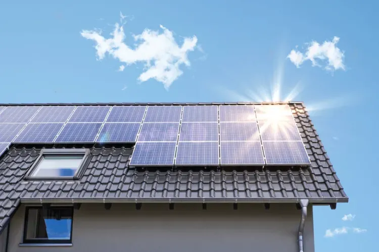 The sun is shining through the solar panels on the roof of a house.