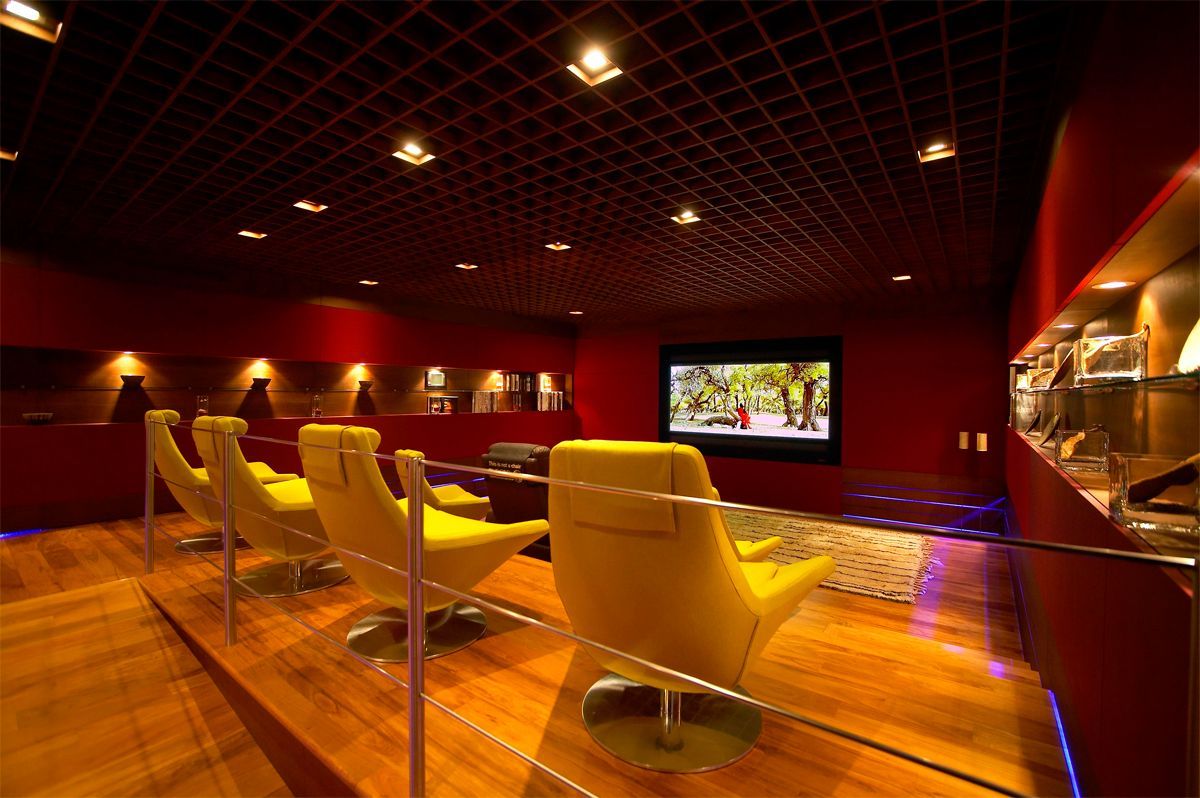 Yellow chairs in a red-walled home theater, with a TV screen displaying a colorful scene.