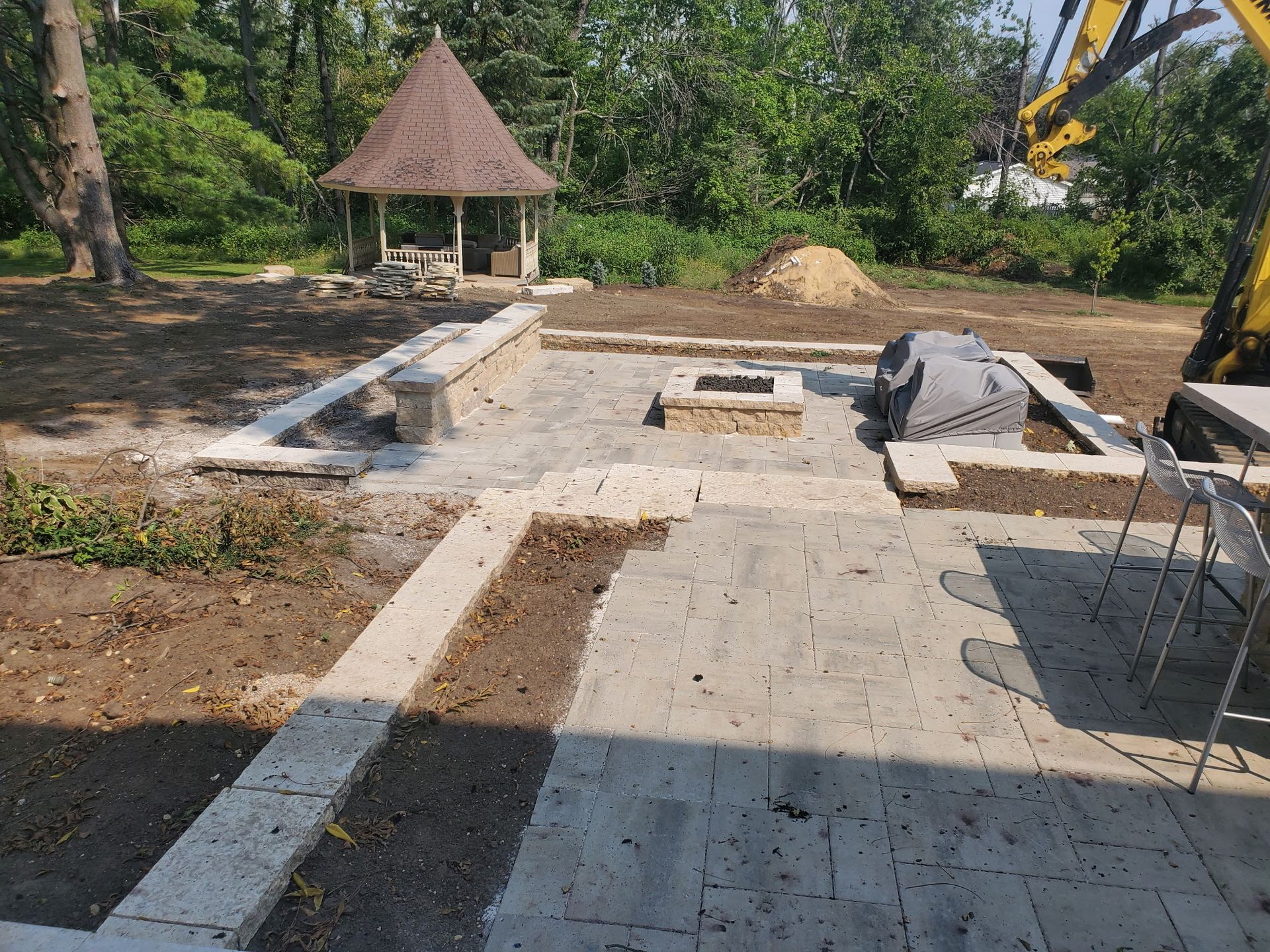 A patio with a fire pit and a gazebo in the background.