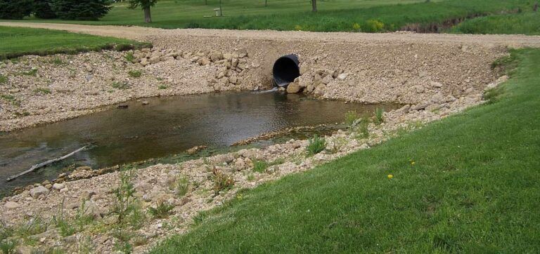 A pipe is draining water into a small stream.
