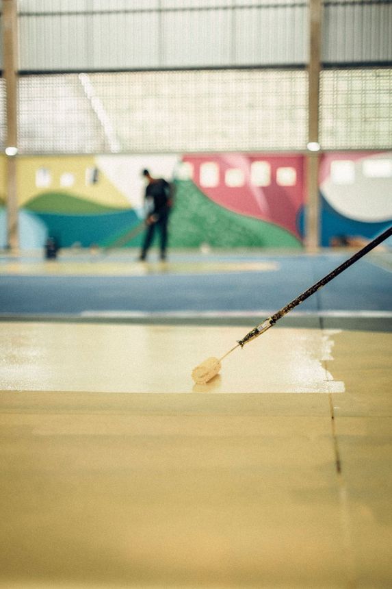 Worker applying epoxy floor coating with a roller in a commercial space