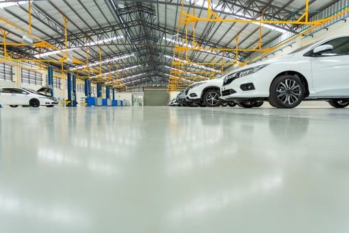 Glossy epoxy-coated commercial garage floor with vehicles parked in a large industrial bay