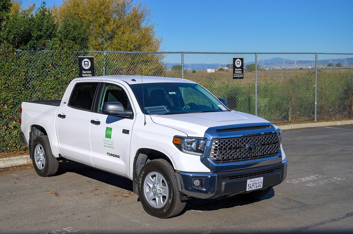 White pickup truck parked outdoors on a paved lot near a fence and trees | Adaptive Fleet Management