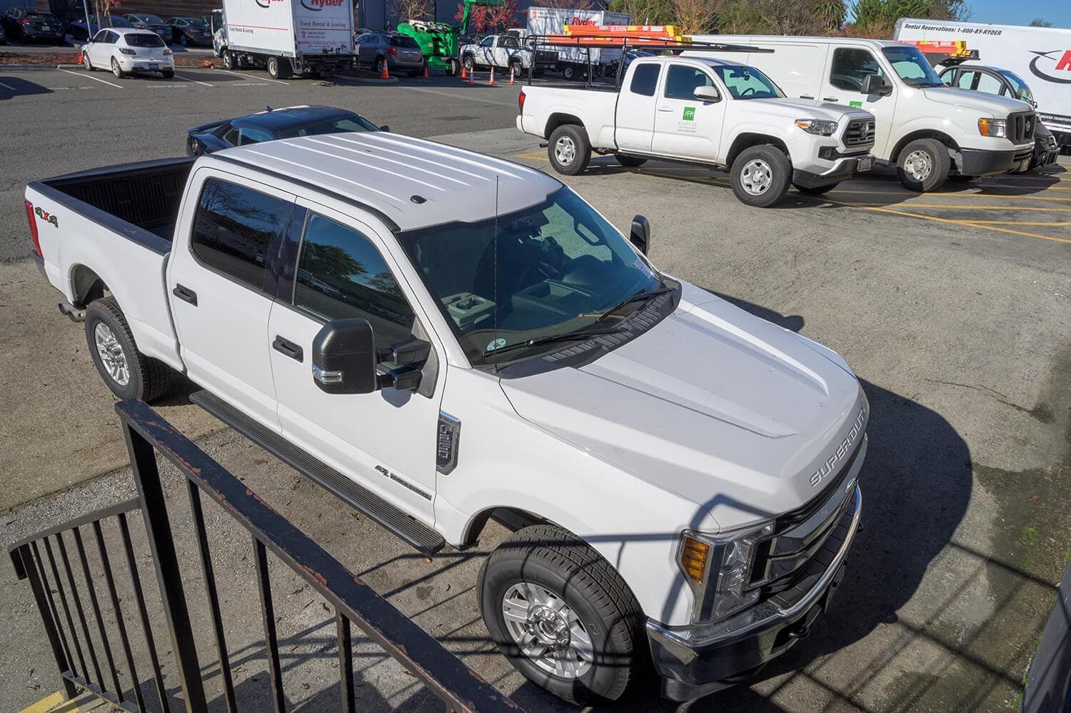 White pickup truck parked in a gravel lot with other work trucks in the background | Adaptive Fleet Management