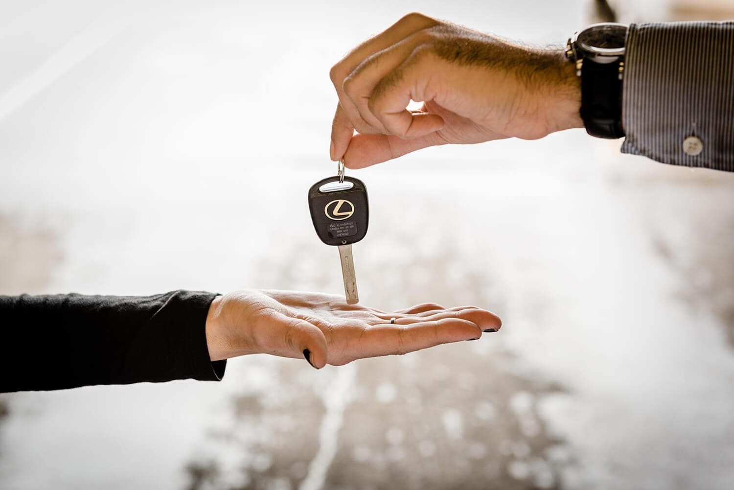 Car key handed from one person to another over an open palm, suggesting a car sale or transfer | Adaptive Fleet Management