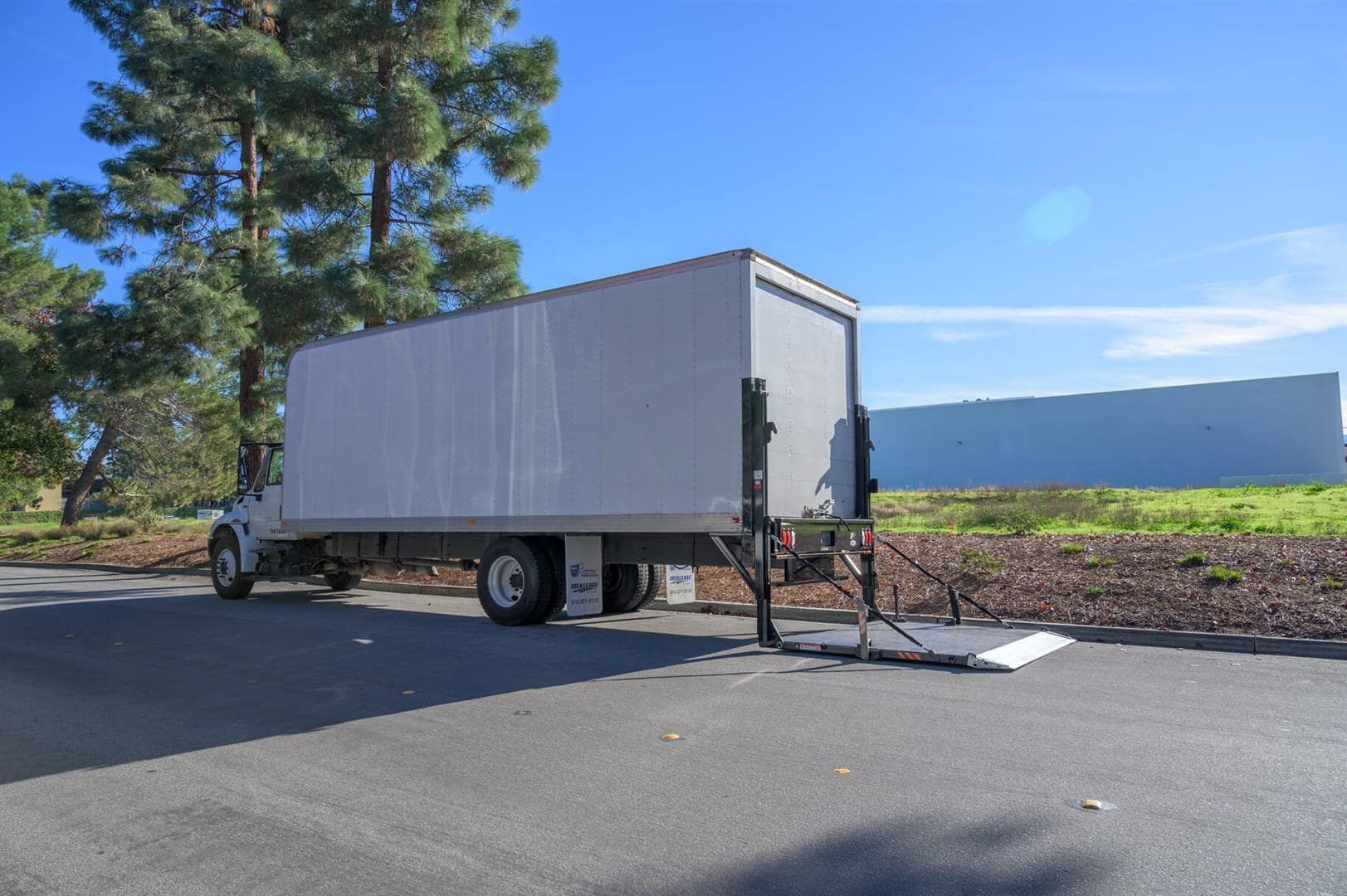 White box trailer parked on a roadside beside a tree and blue sky | Adaptive Fleet Management