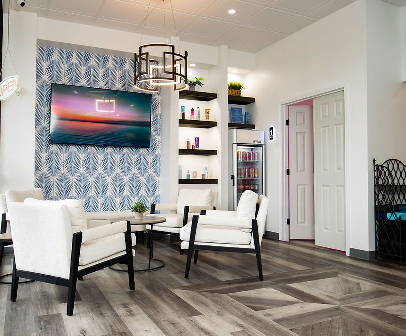 Modern lounge with white chairs, wall art, shelving, and patterned blue accent wall on wood-look floor.