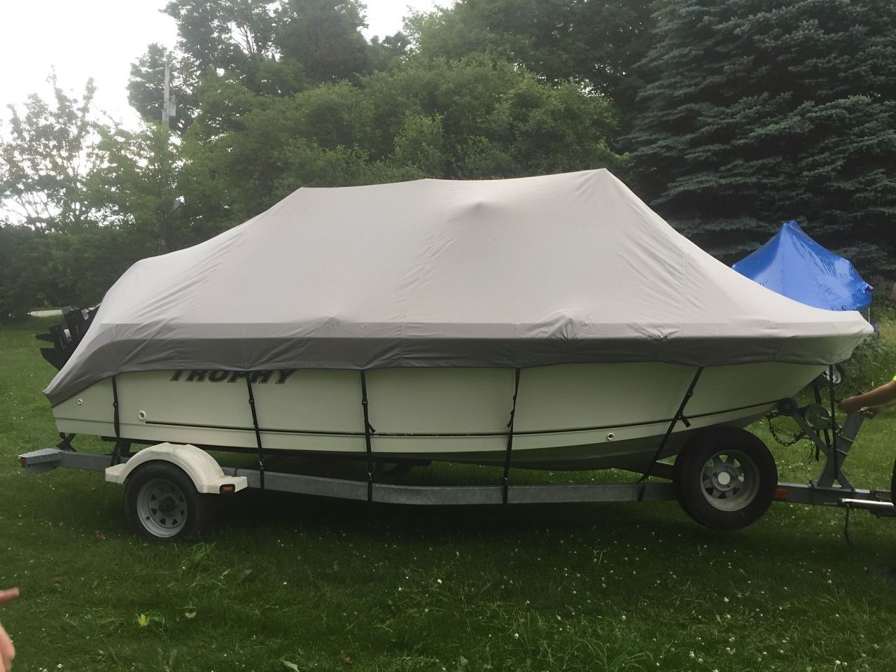 A boat with a cover on it is parked in the grass