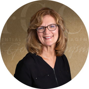 Woman with glasses smiles; brown hair, black shirt, in a circular frame.
