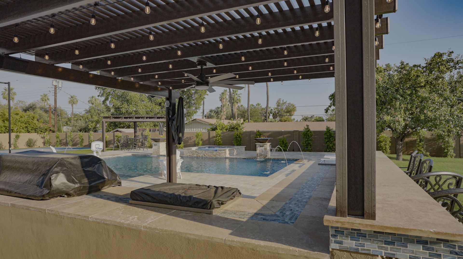 A large swimming pool with a pergola over it.
