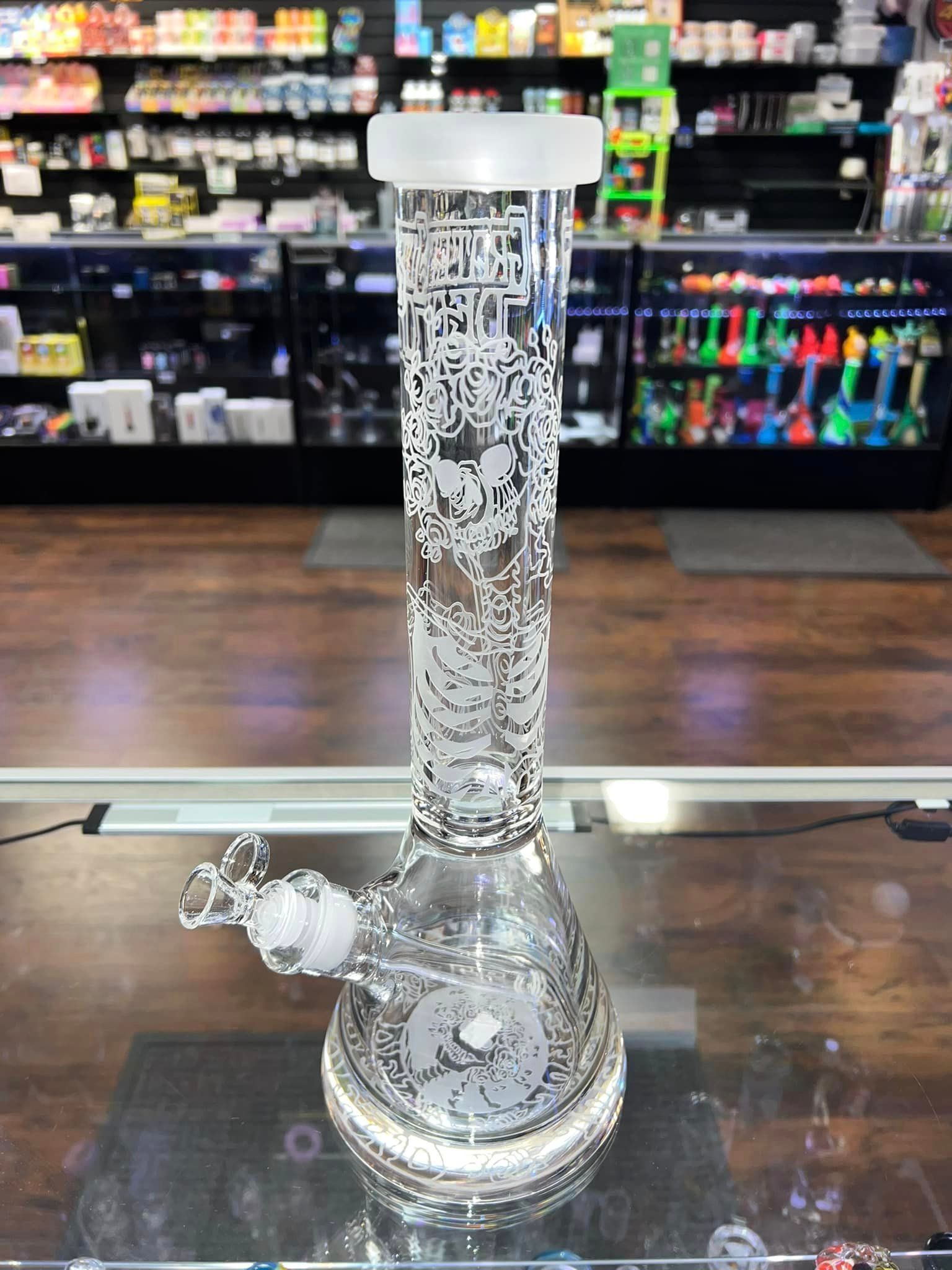 A glass bong is sitting on a glass table in a store.