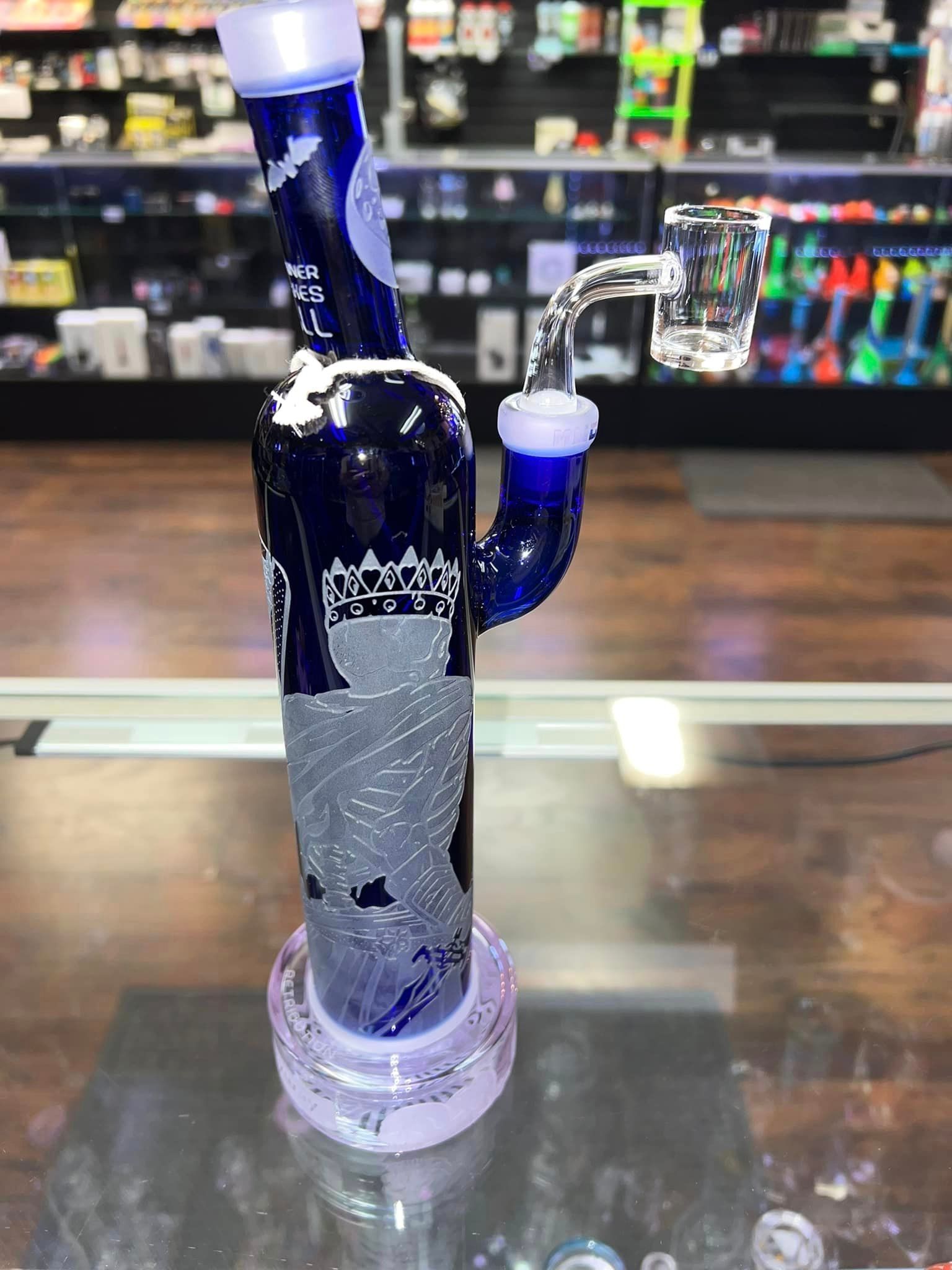 A blue glass pipe is sitting on top of a glass table.