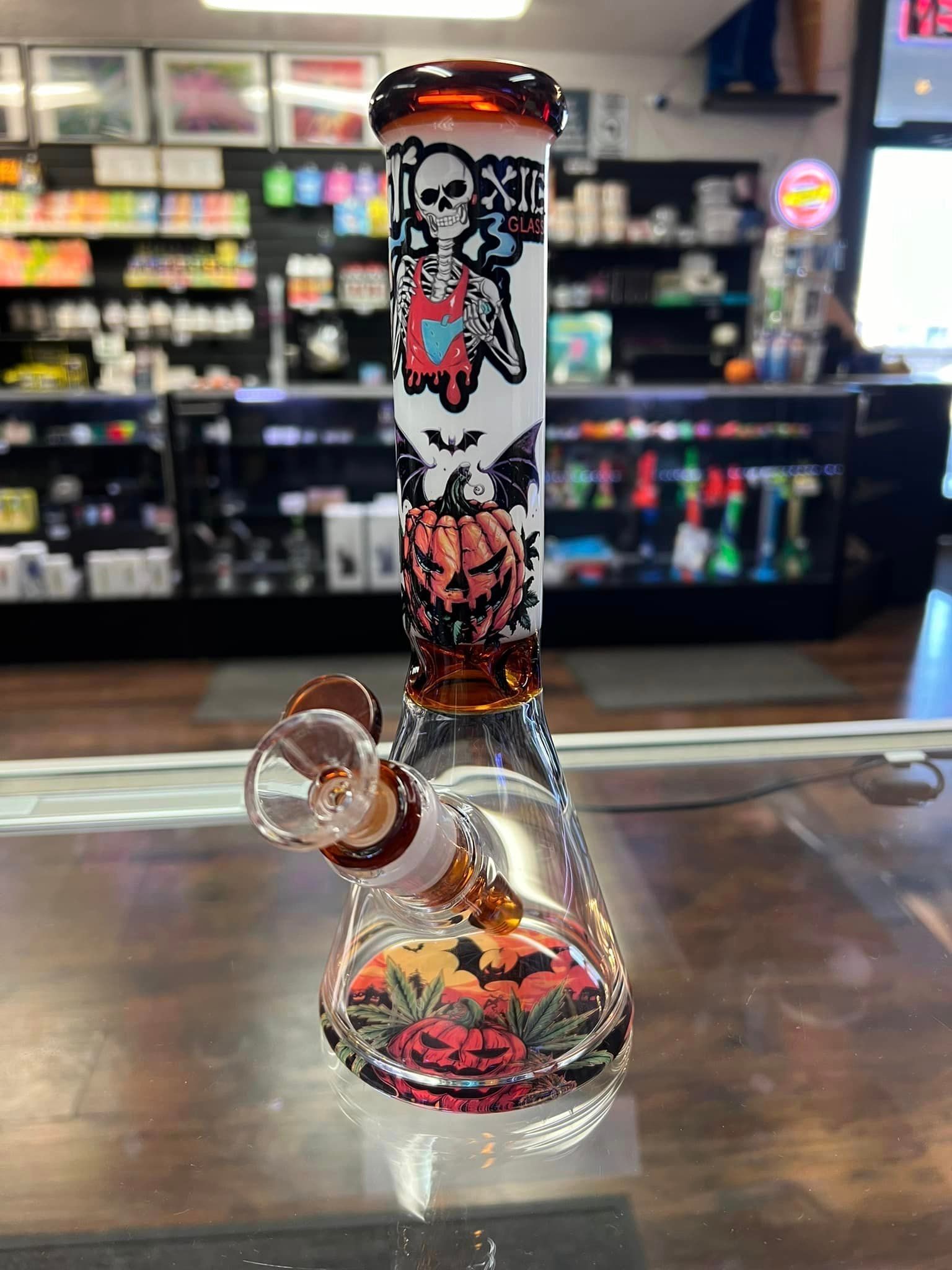 A glass bong is sitting on a glass table in a store.