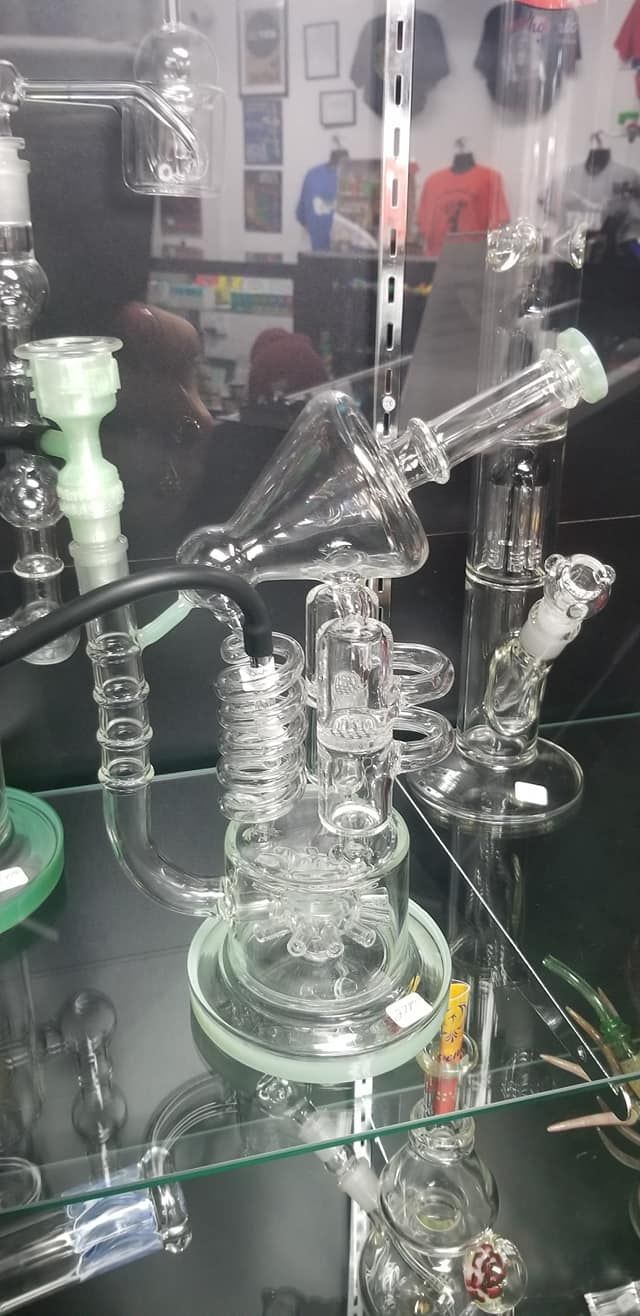 A glass pipe is sitting on a glass shelf in a store.