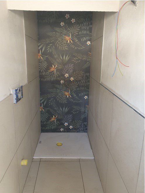 Bagno in costruzione con parete decorativa con motivi floreali e piastrelle beige.