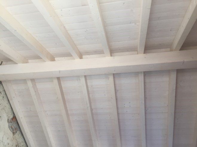 Soffitto in legno con travi e travicelli a vista. Tonalità del legno chiaro.