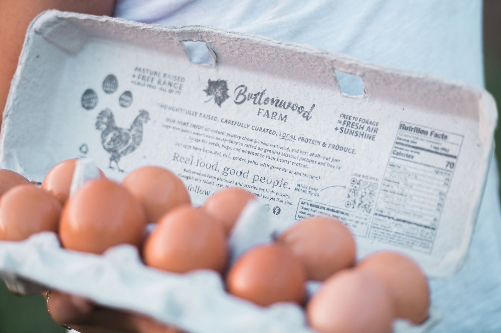 A person is holding a carton of eggs in their hands.
