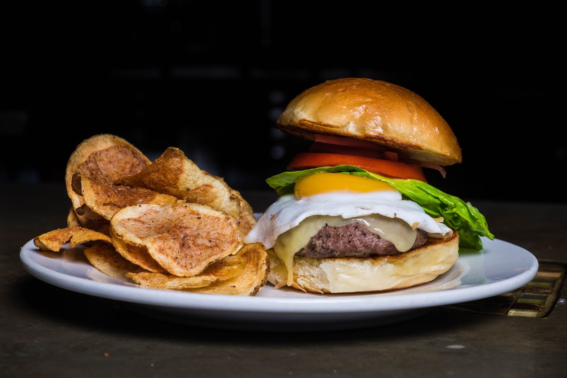 A hamburger and chips on a white plate on a table.